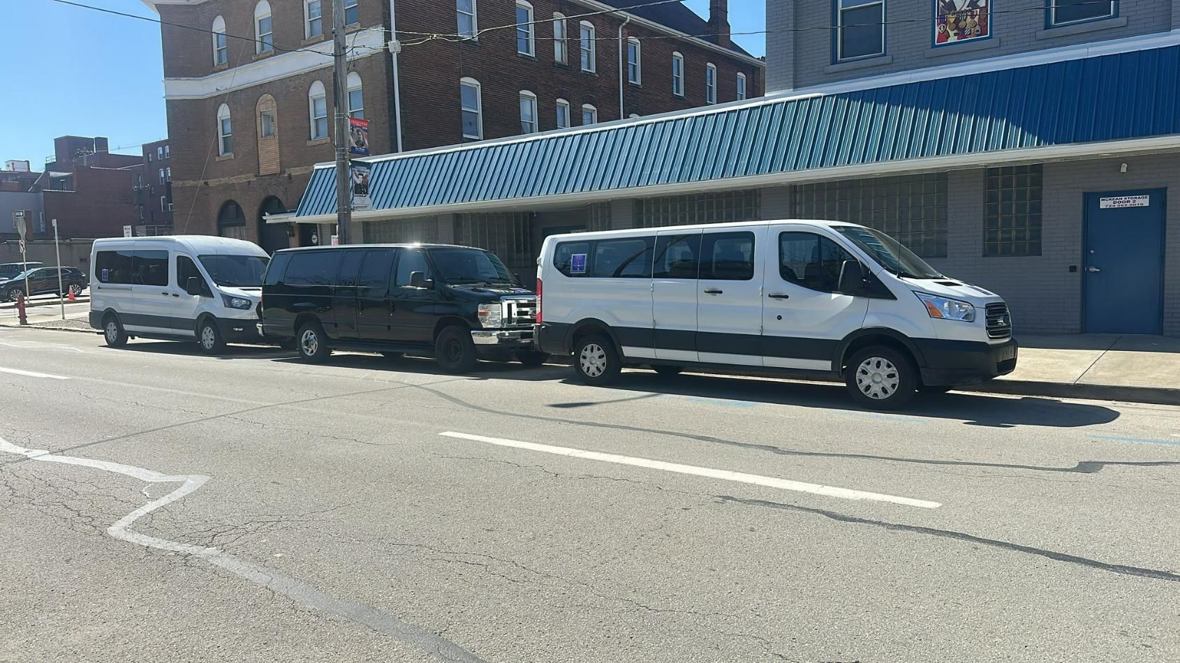 Three white vans are parked next to each other in a parking lot.