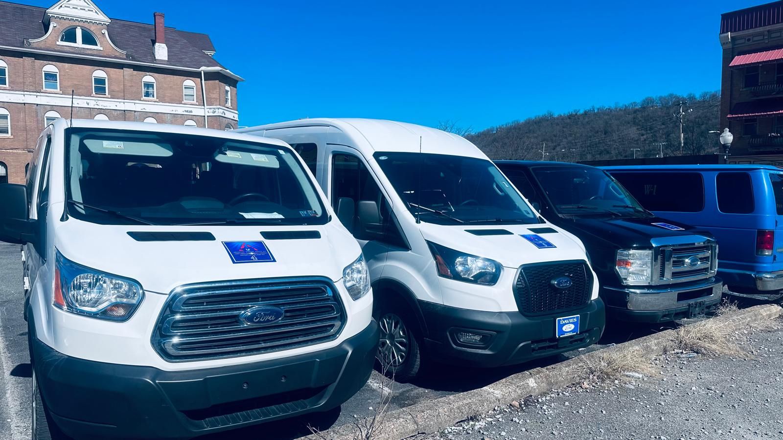 Three white vans are parked next to each other in a parking lot.
