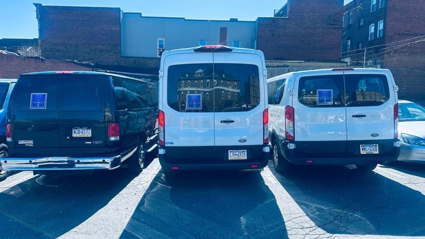 Three vans are parked next to each other in a parking lot.