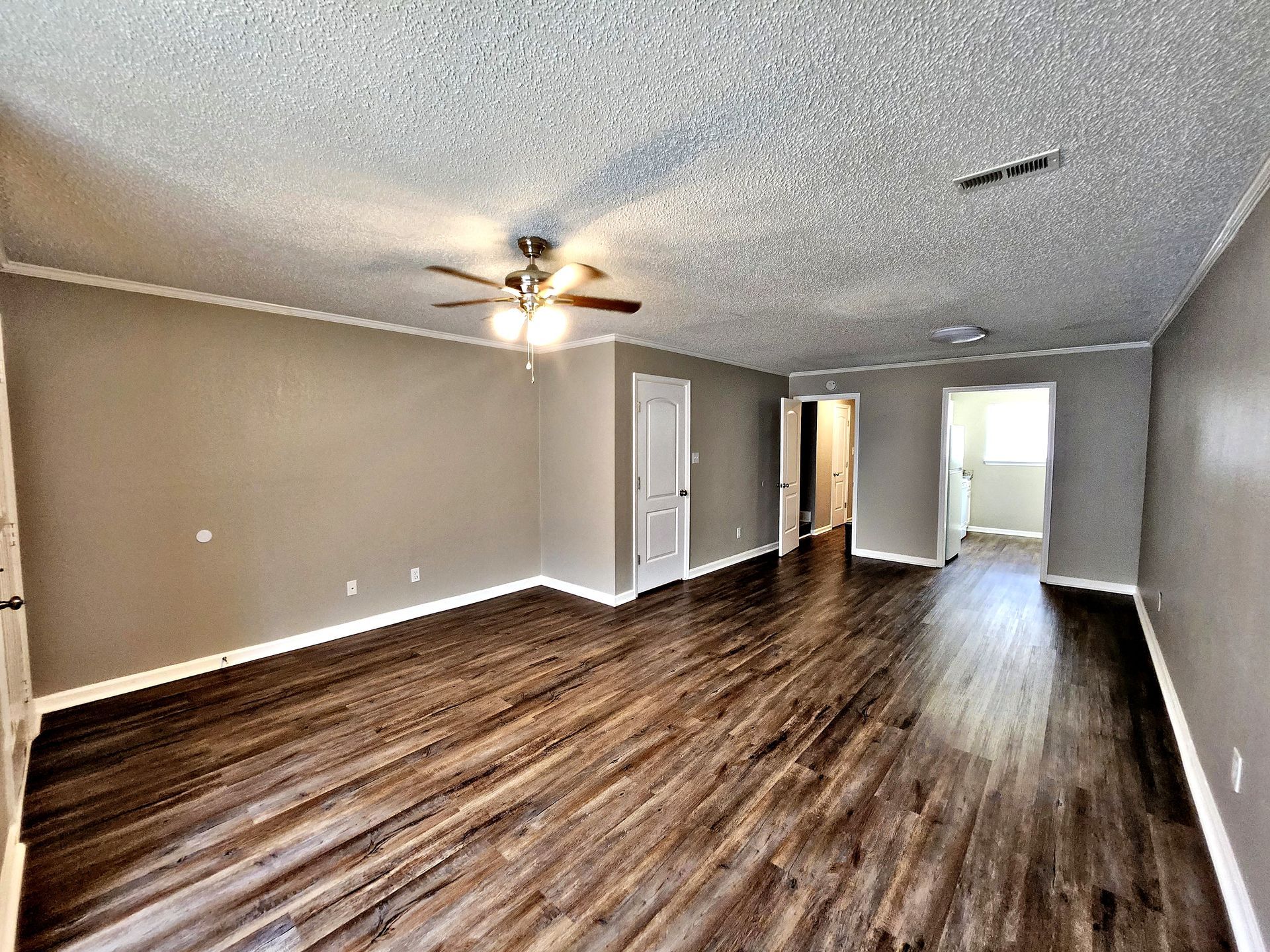 An empty living room with hardwood floors and a ceiling fan.
