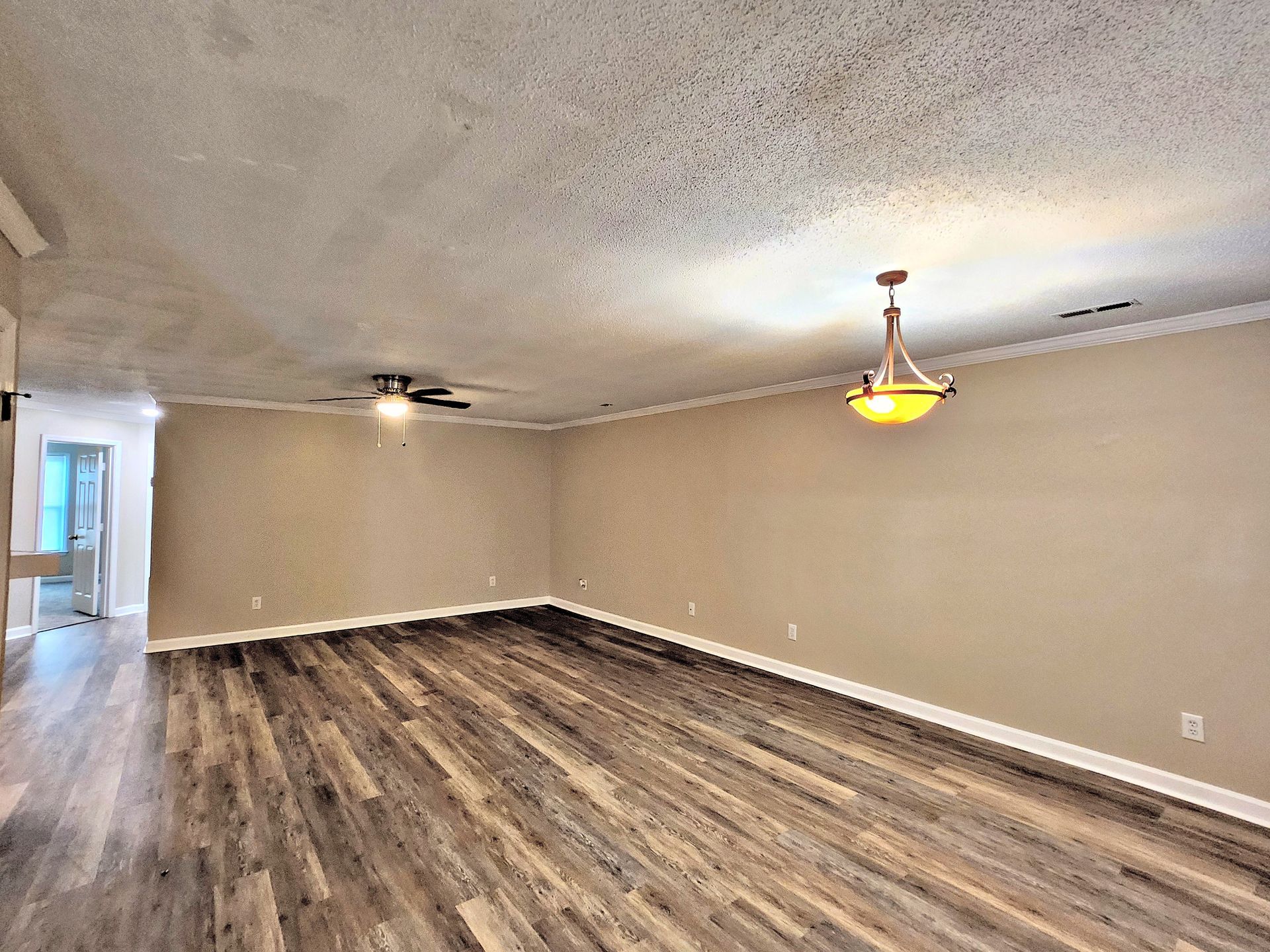 An empty living room with hardwood floors and a ceiling fan.
