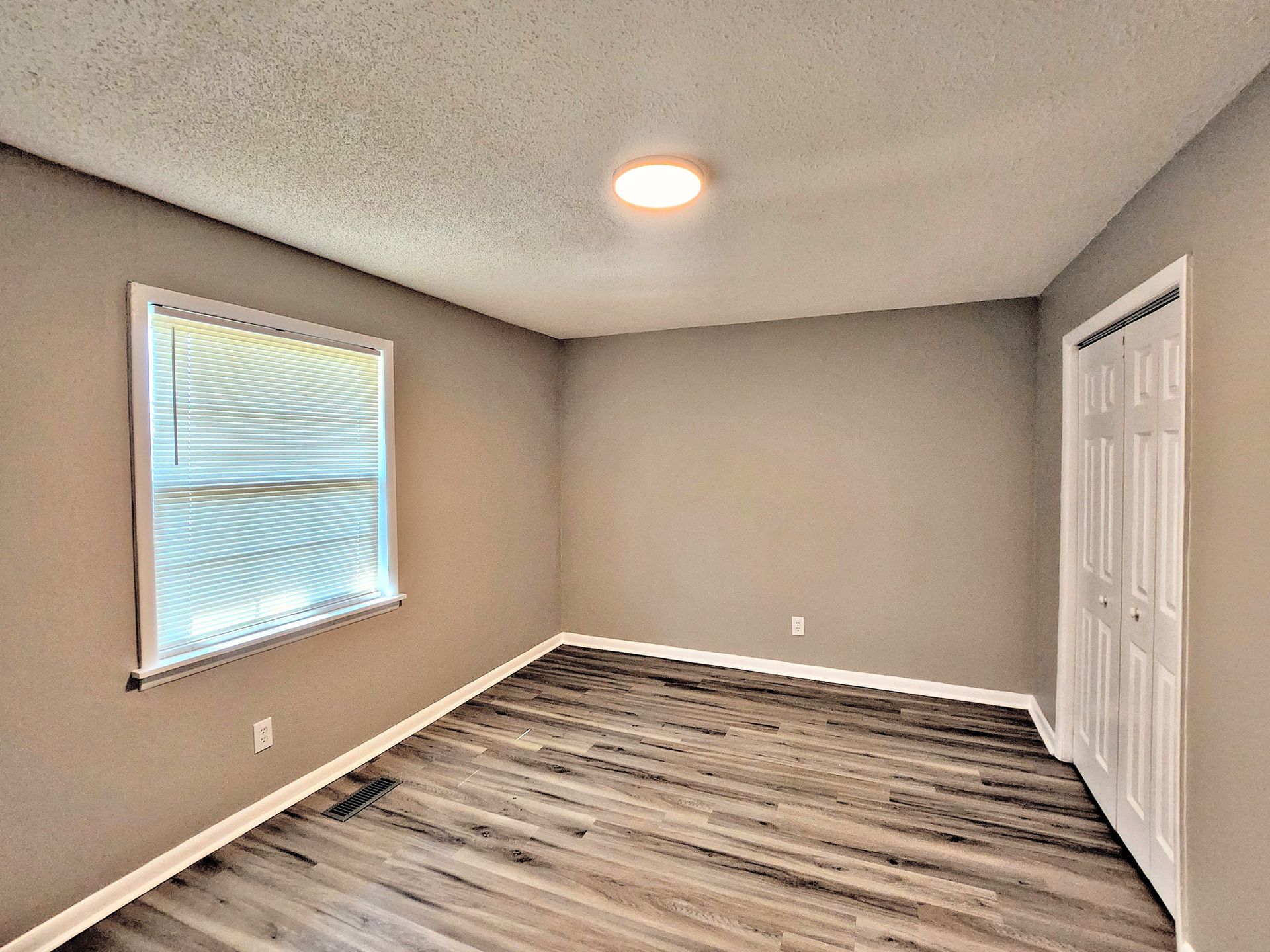 An empty room with hardwood floors and a window.