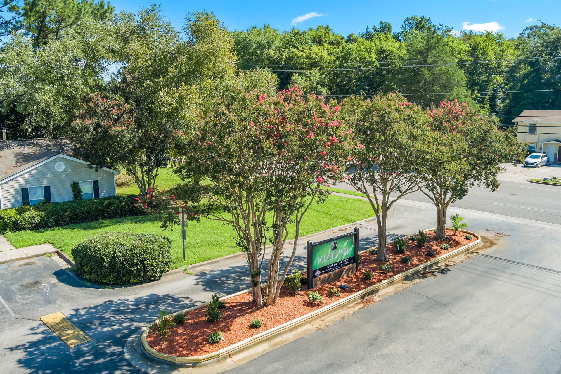 An aerial view of a parking lot with trees and a sign.