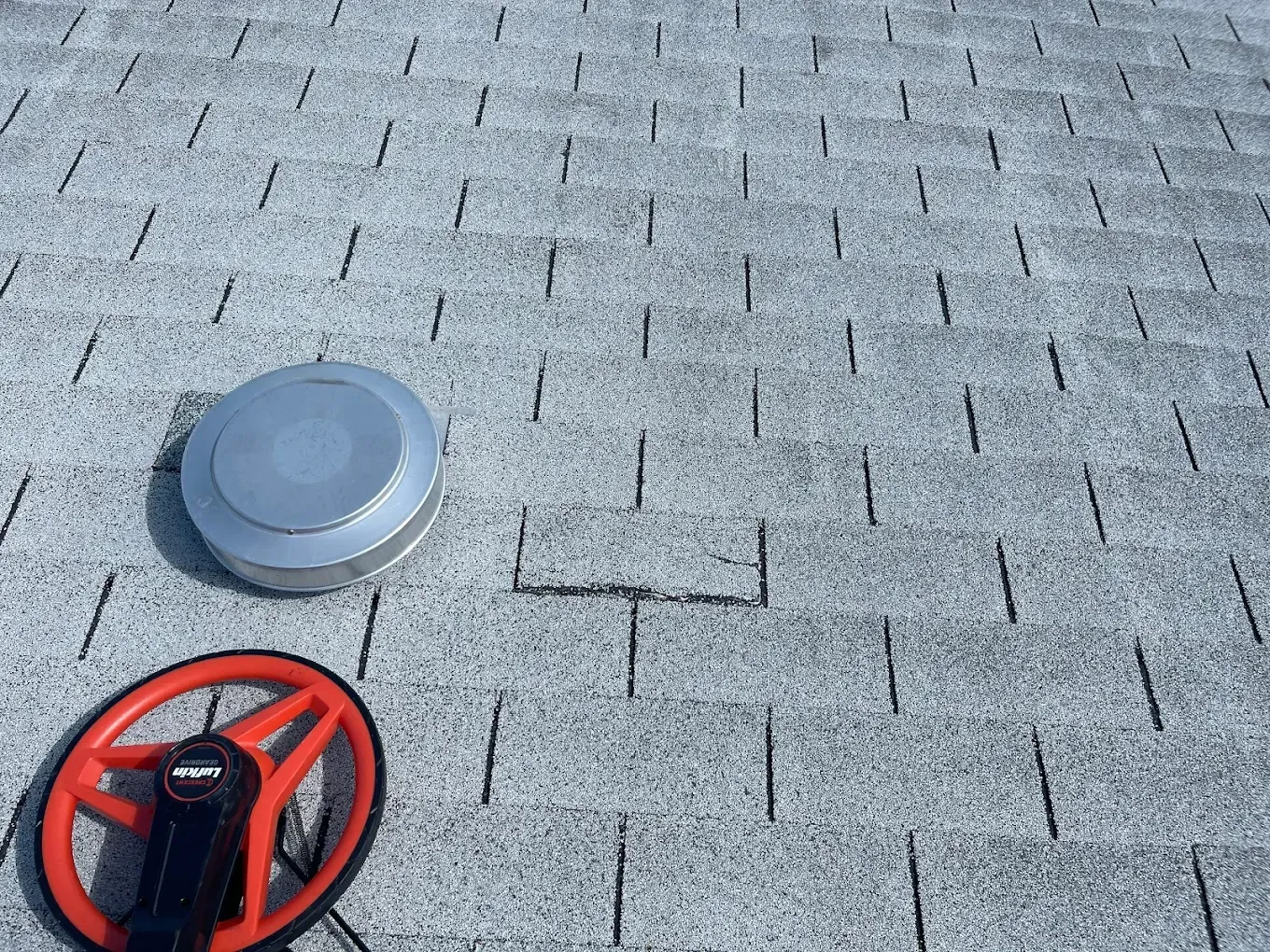 A roof with a hole in it and a fan on it.