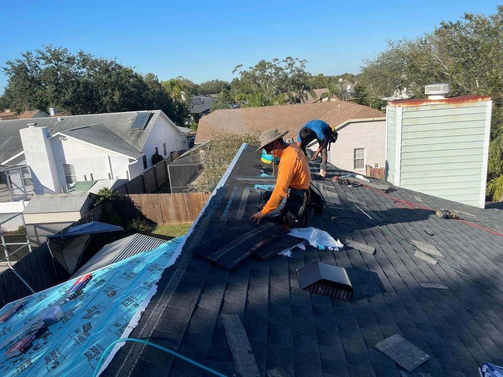 Two men are working on a roof of a house.