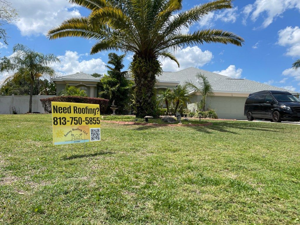 A house with a palm tree and a sign in front of it.