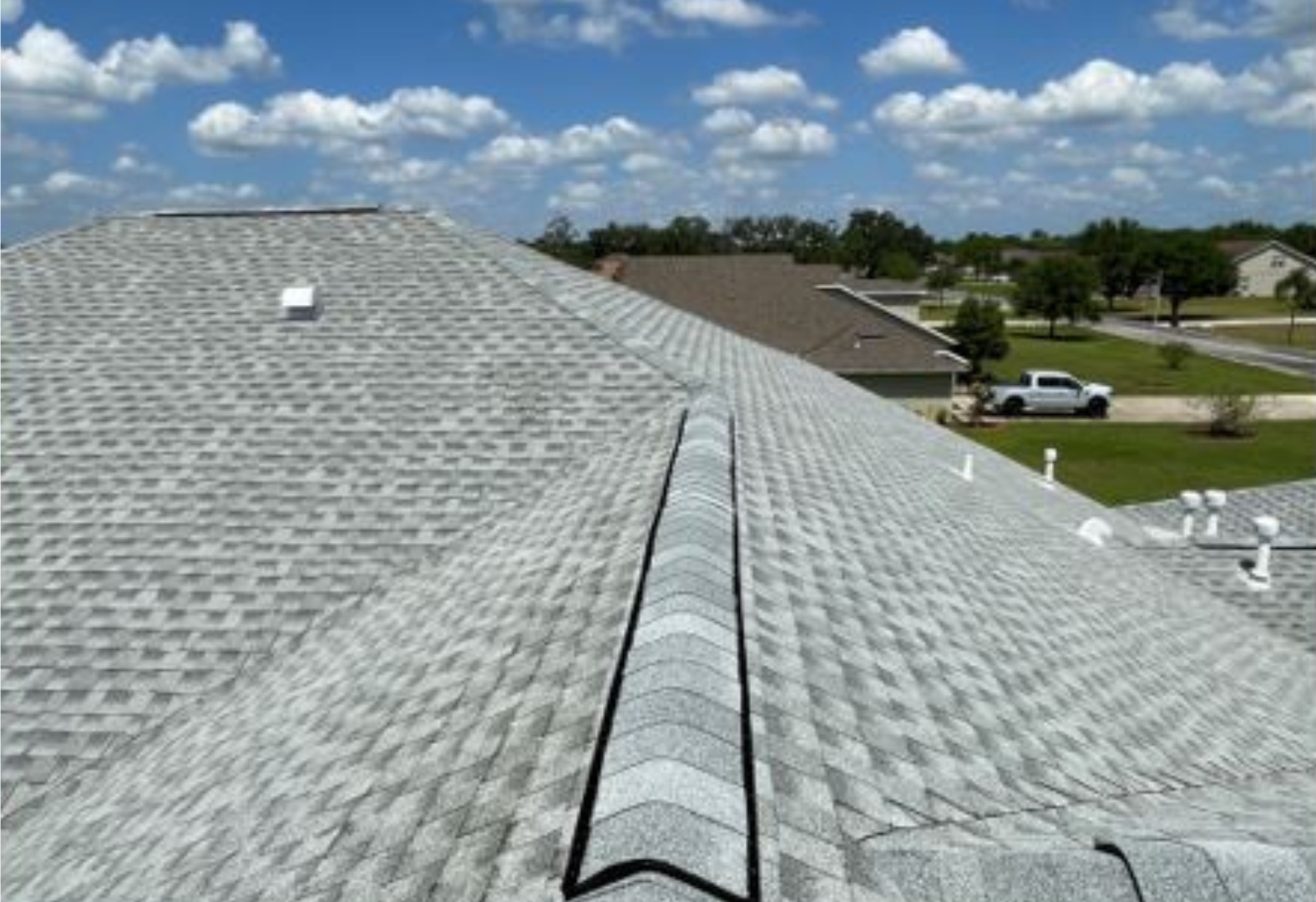 The roof of a house with a white truck parked in the driveway.