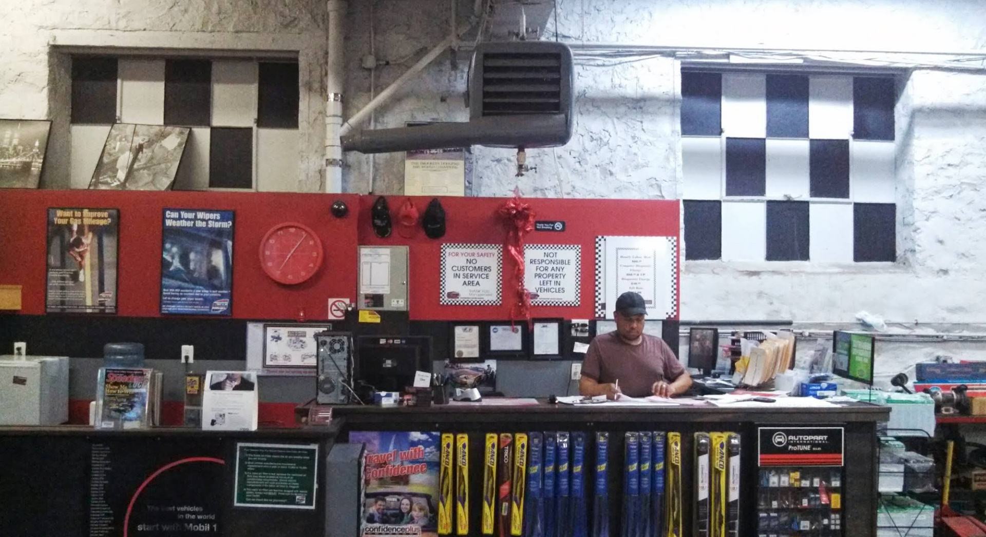 Inside of auto parts store; counter with a person working. Checkered patterns and tools on display. | Bovan’s Auto Services