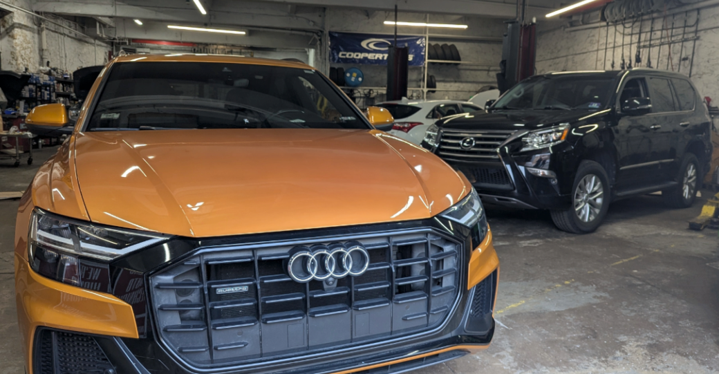 Orange Audi Q8 SUV and black SUV parked inside a garage. | Bovan’s Auto Services
