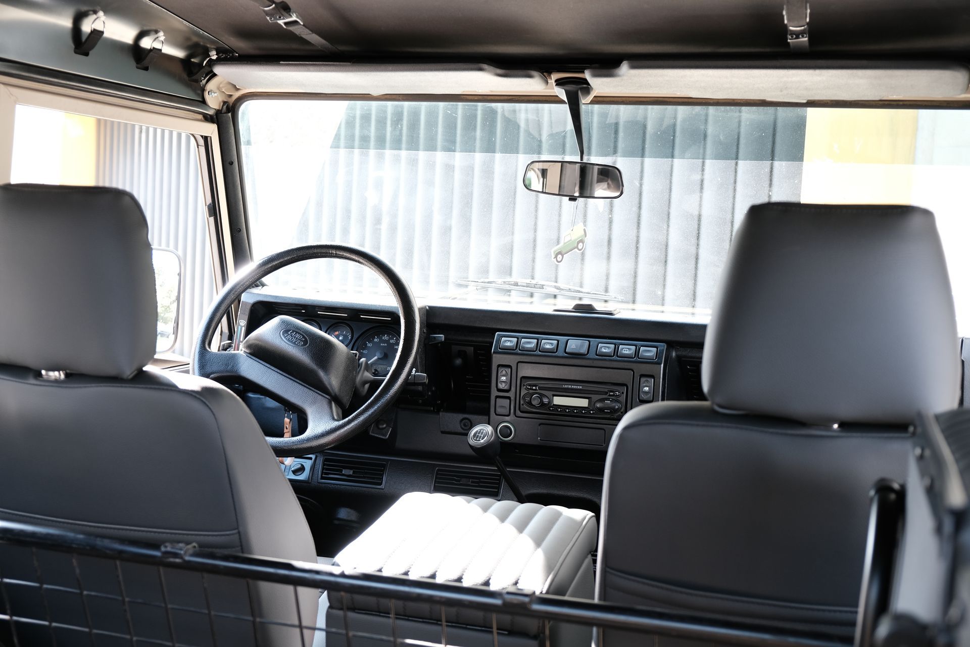 Intérieur d'un Land Rover Defender, avec sièges, volant et tableau de bord noirs.