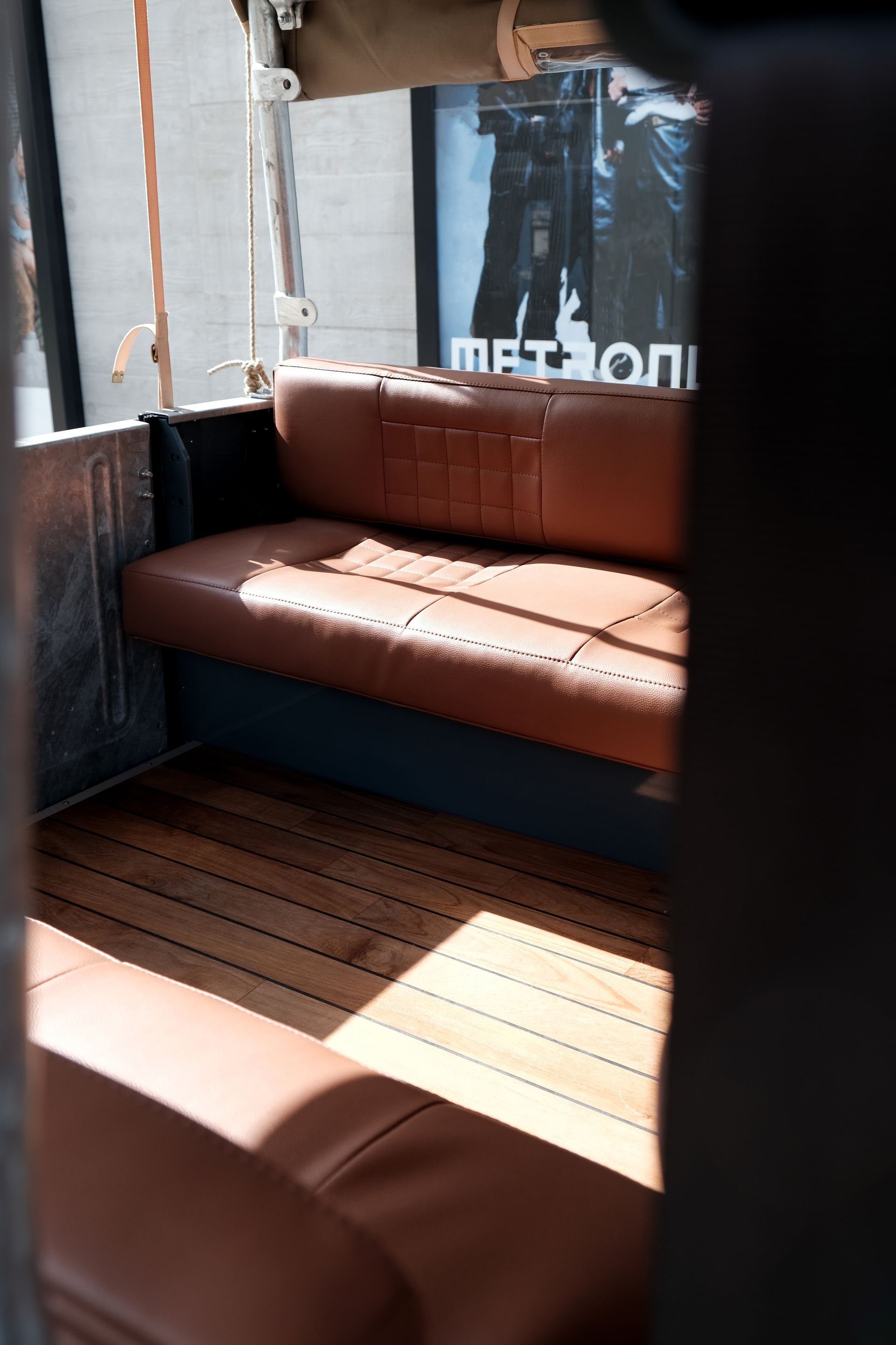 À l'intérieur d'un véhicule : sièges en cuir marron, plancher en bois. La lumière du soleil entre à flots.