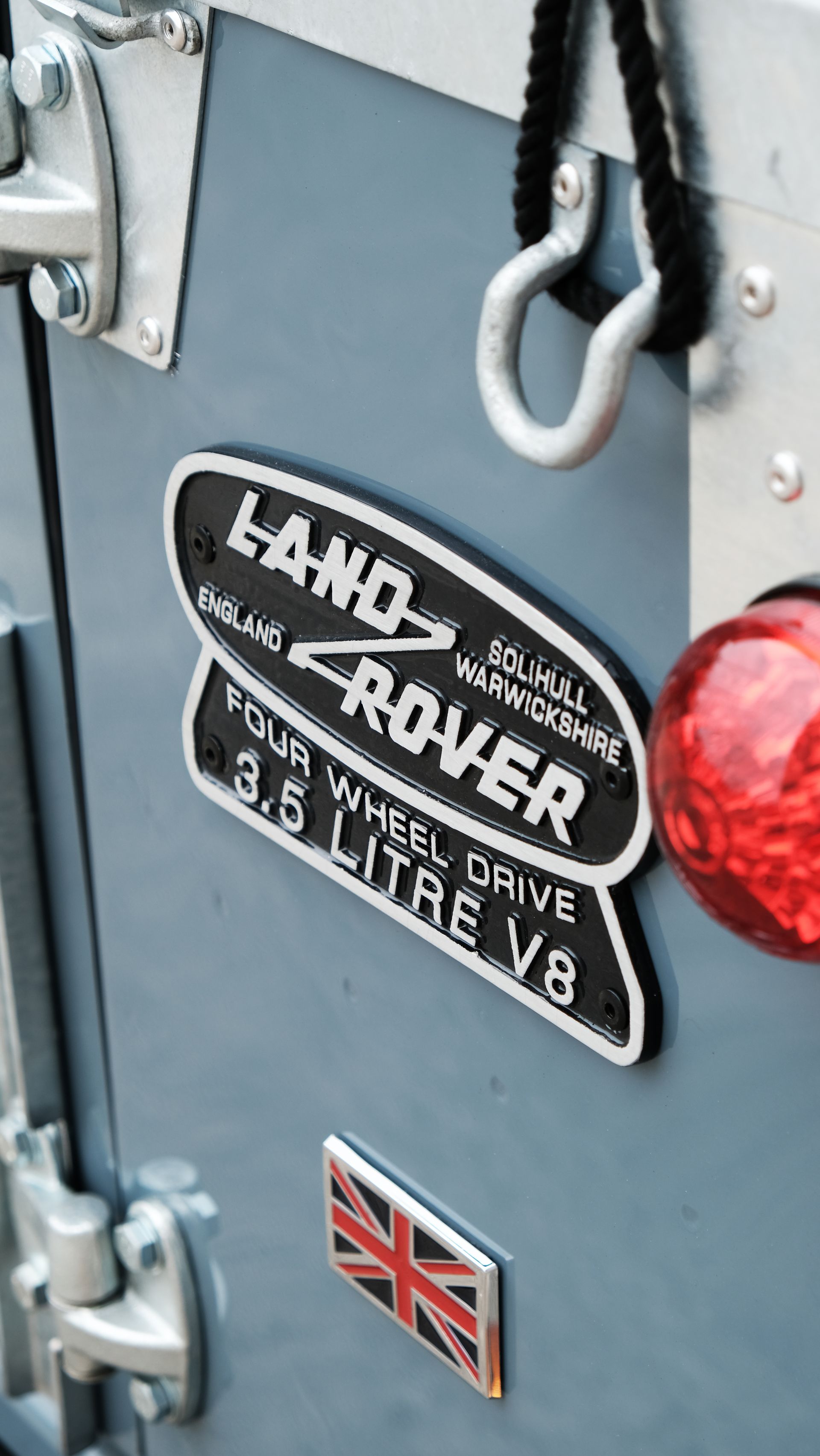 Emblème Land Rover, insigne Union Jack et feu arrière rouge sur un véhicule bleu.