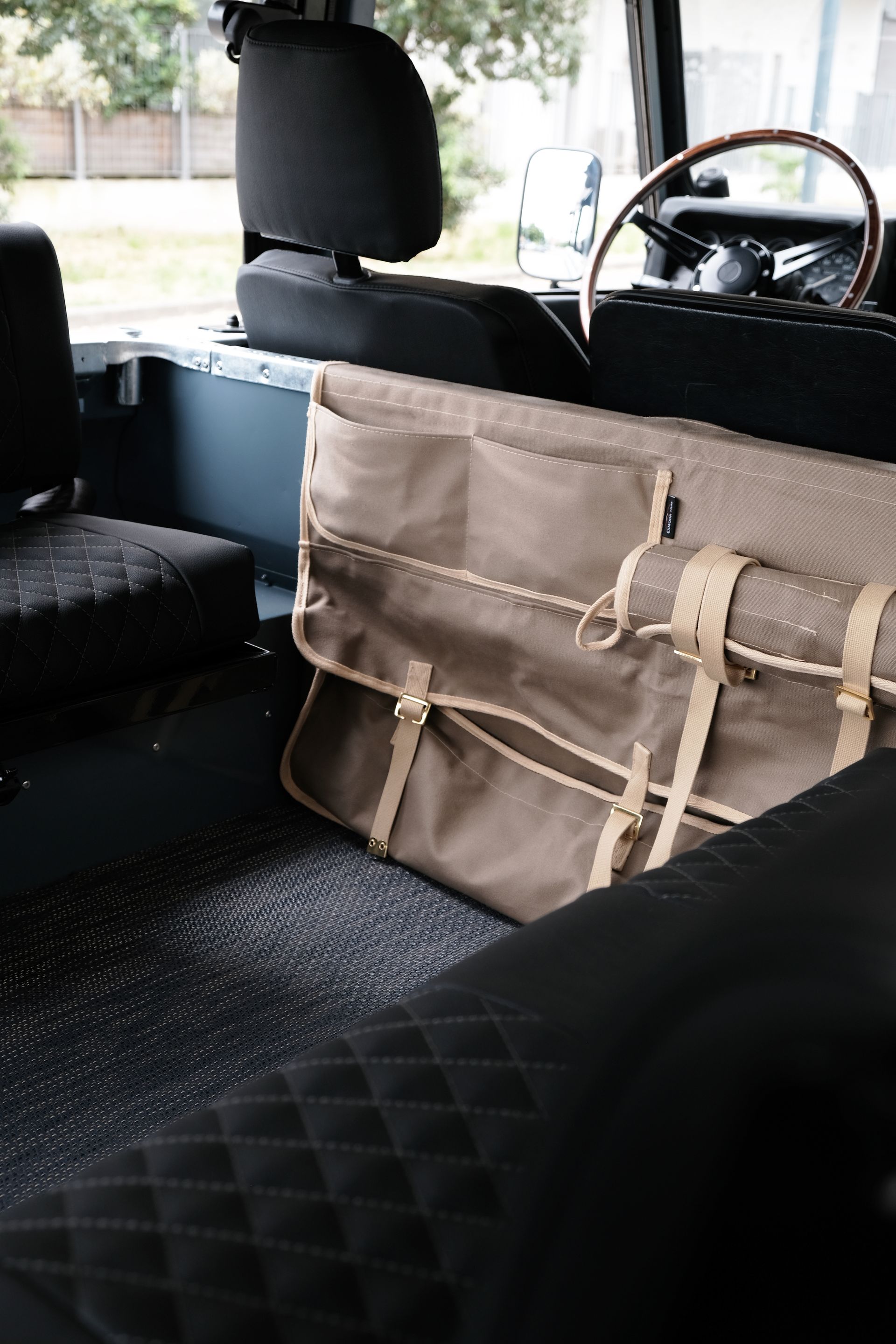 Sac en toile beige avec boucles à l'intérieur d'un véhicule; siège et plancher noirs.