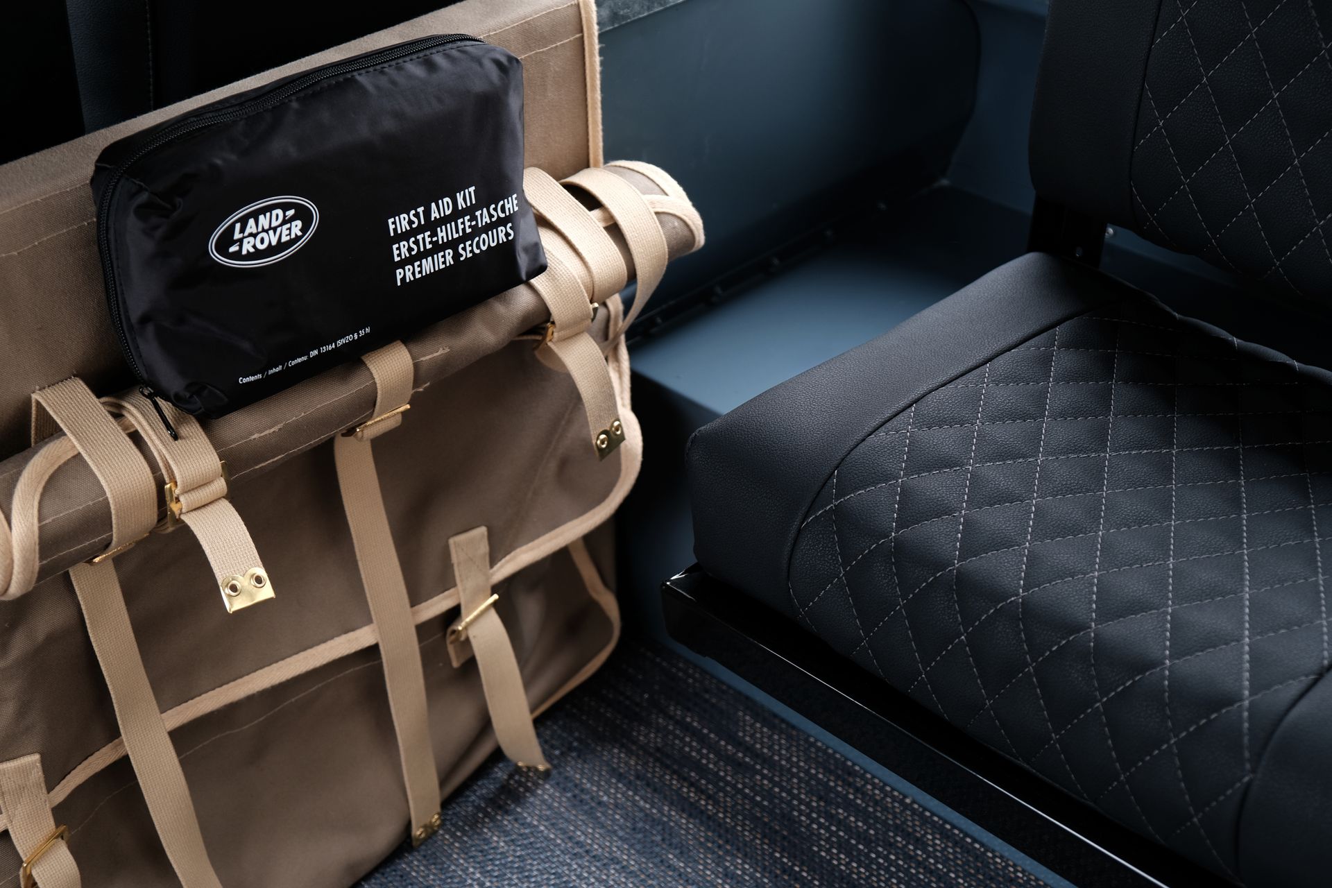 Des sacs de voyage beiges et noirs se trouvent à l'intérieur d'un véhicule, laissant apparaître des sièges noirs matelassés.