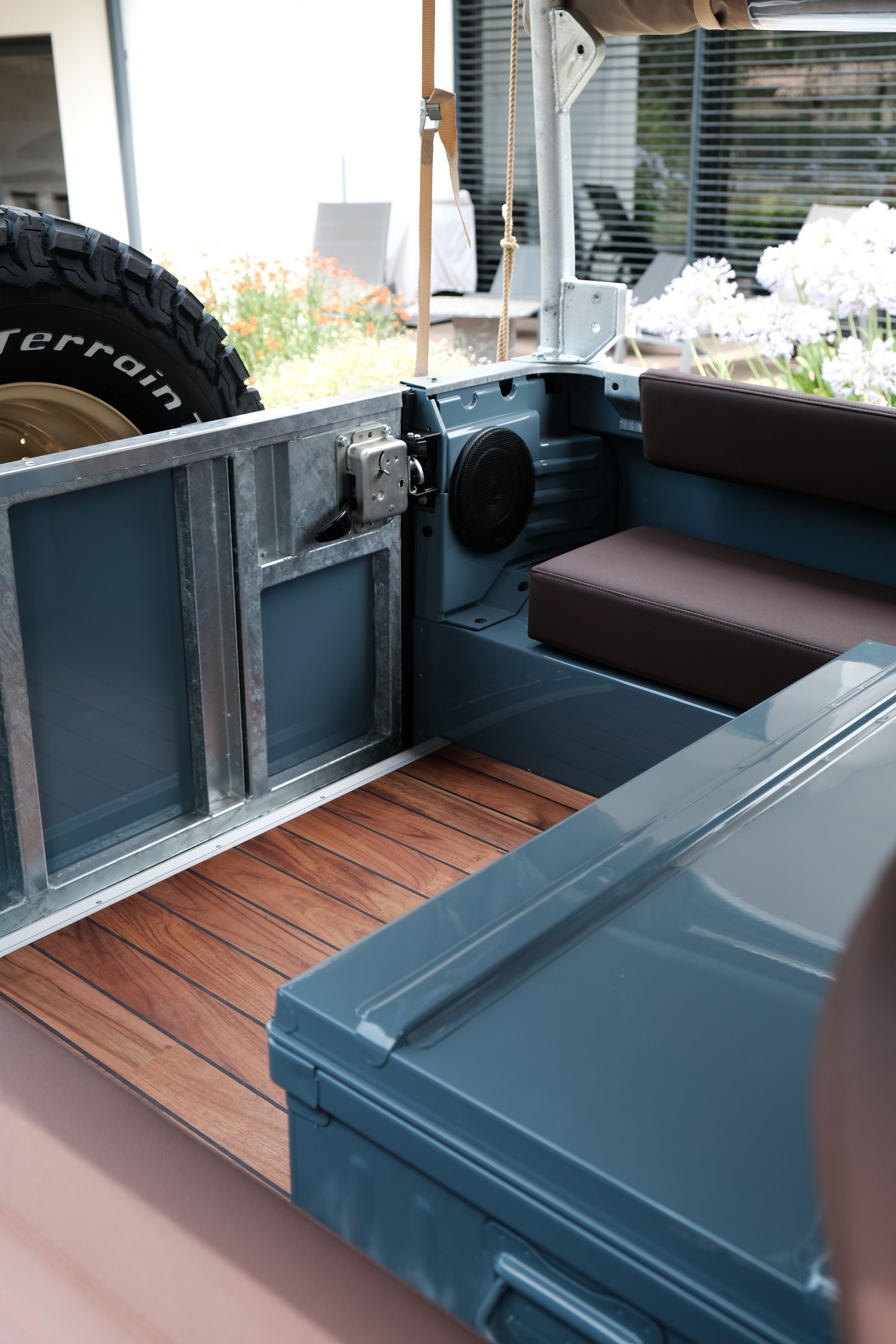 Intérieur d'un véhicule vintage avec plancher en bois, panneaux bleus et sièges marron.