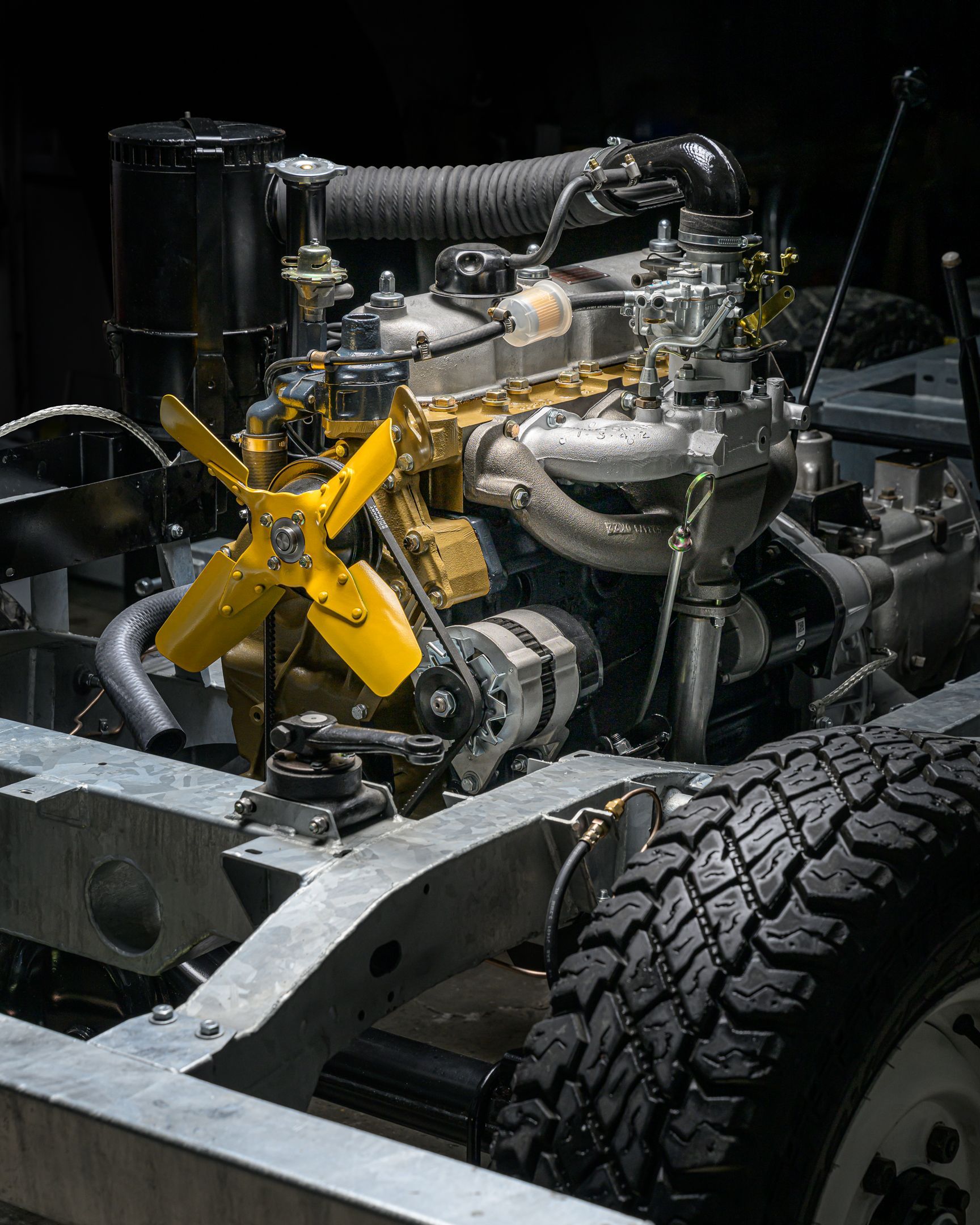 Ensemble ventilateur et moteur à pales jaunes monté sur un cadre en métal argenté. Pneu noir au premier plan.