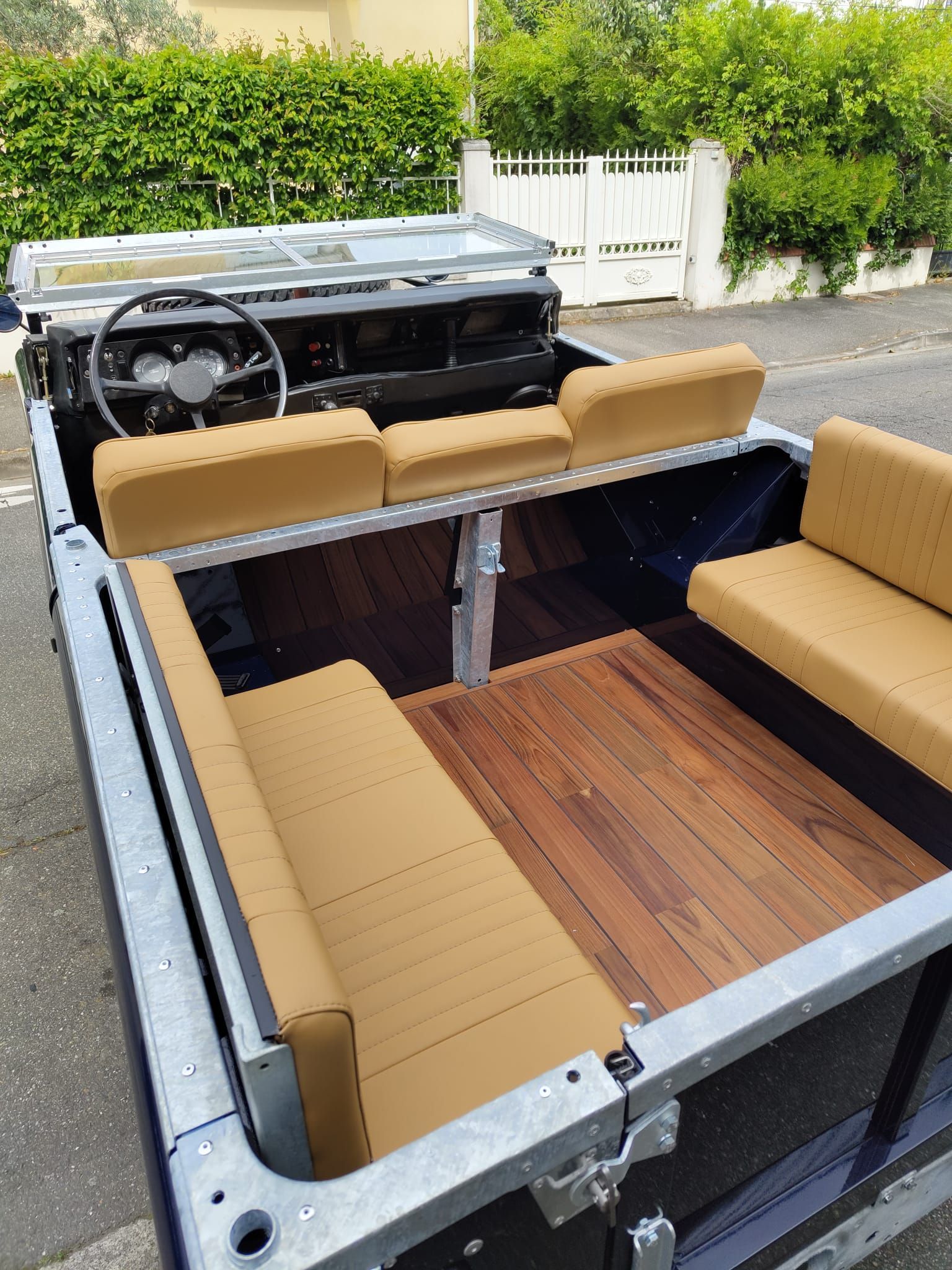 Land Rover personnalisé, design ouvert avec plancher en bois et sièges beiges, dans une allée.