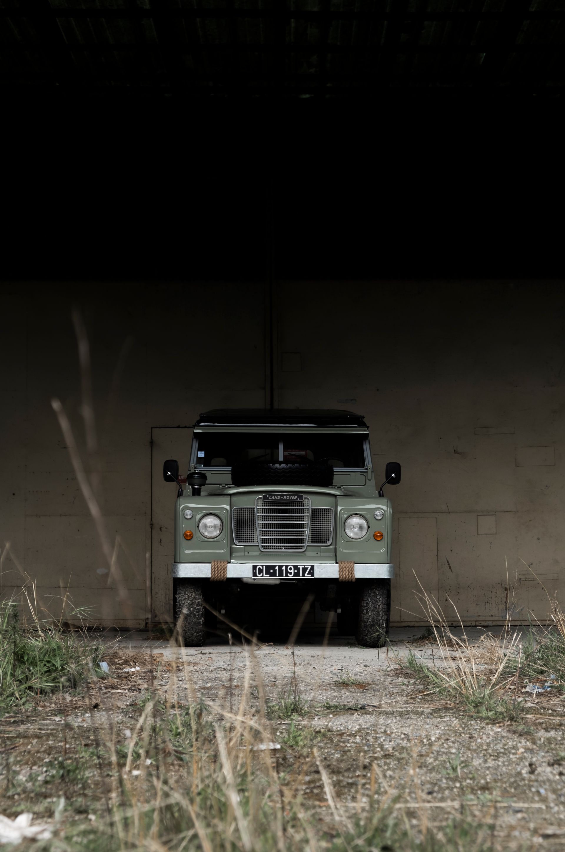 Land Rover Defender vert garé dans un tunnel sombre en béton.