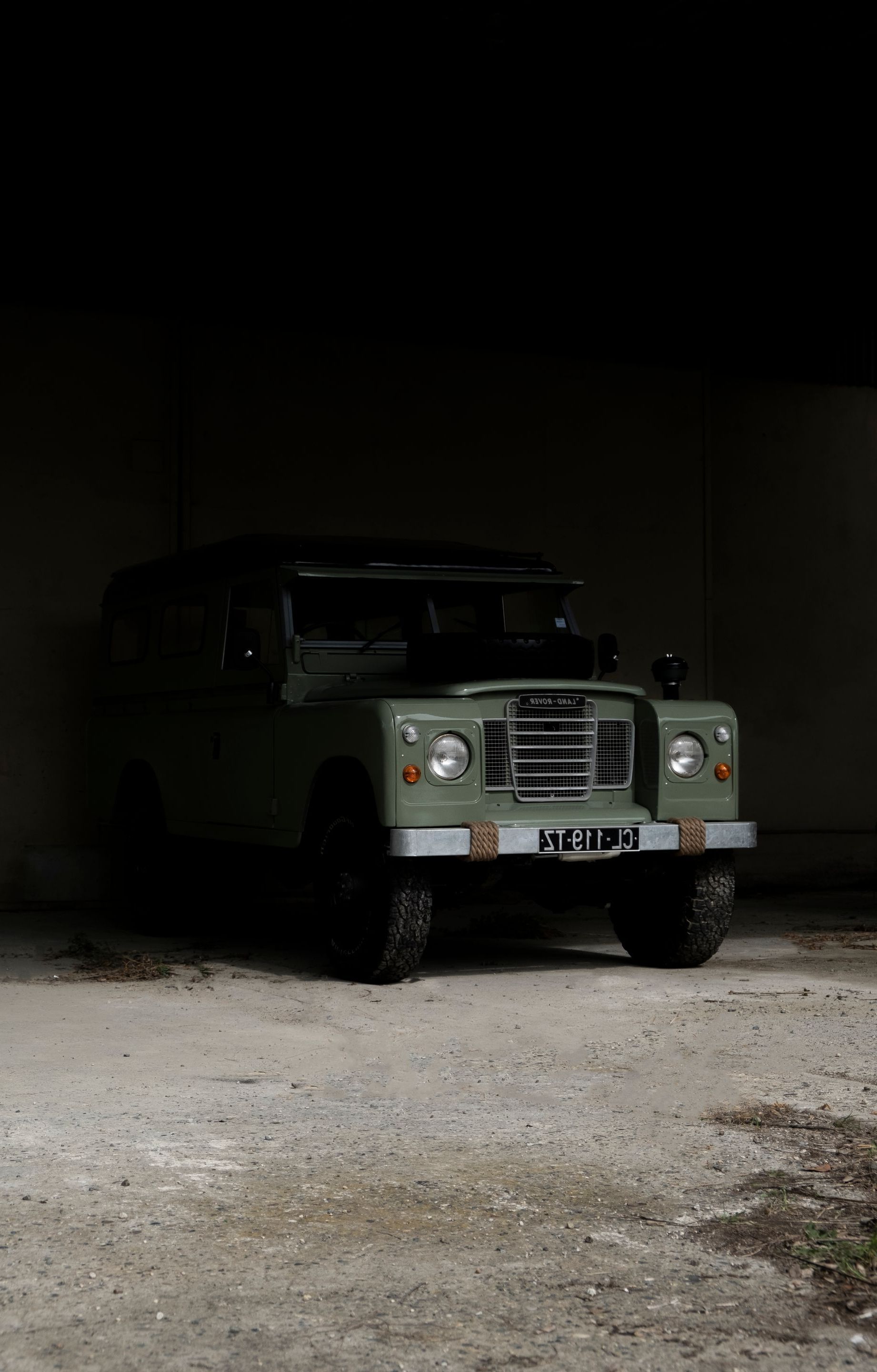 Land Rover vert garé à l'intérieur d'un bâtiment en béton faiblement éclairé.
