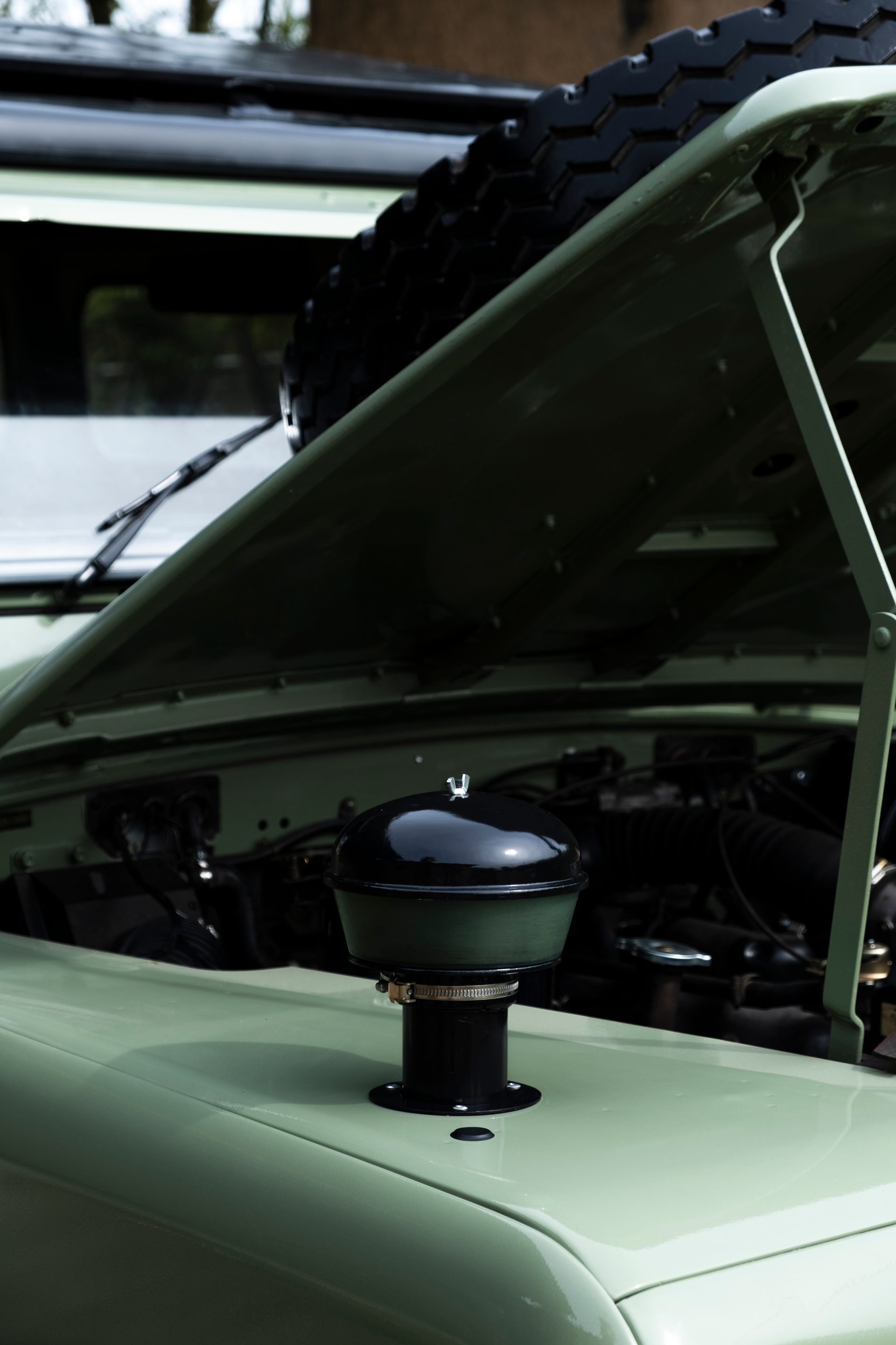 Land Rover vert avec le capot relevé, montrant le moteur et le filtre à air.