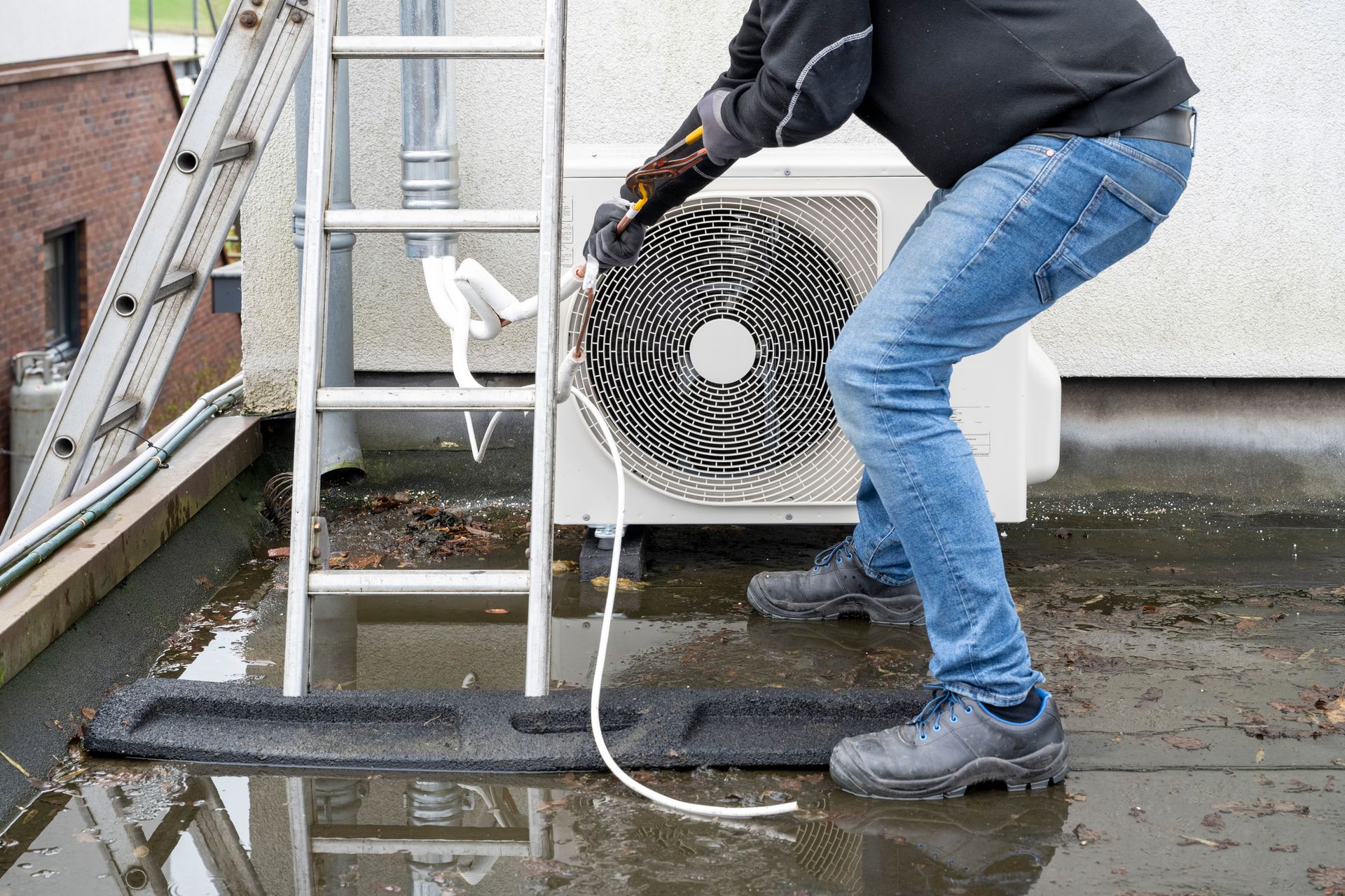 A technician is fixing an air conditioning unit, demonstrating expertise in AC installation.