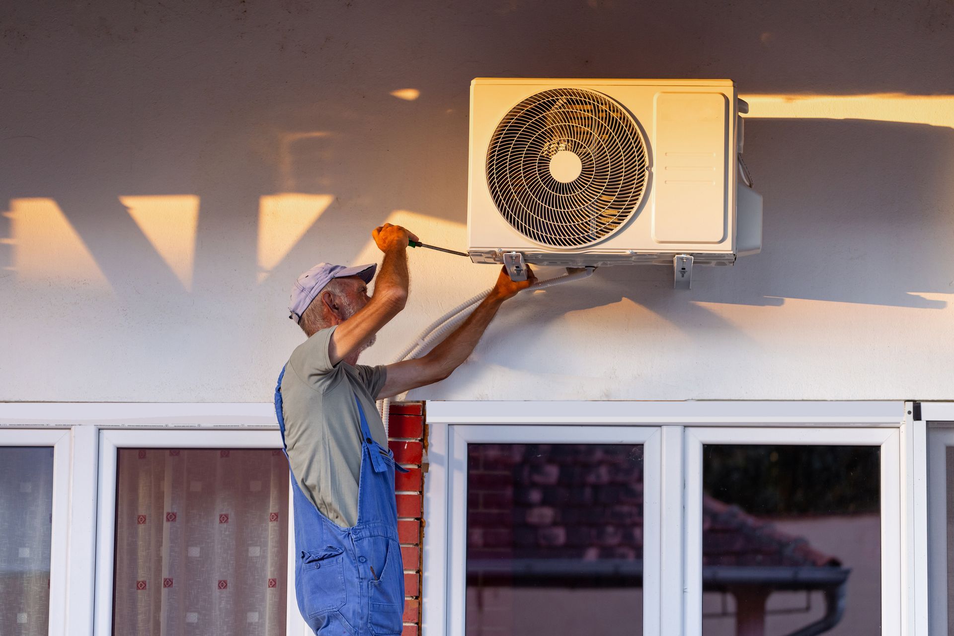 A technician installing an air conditioning unit outdoors, ensuring proper setup on a sunny day. A technician installing an air conditioning unit outdoors, ensuring proper setup on a sunny day.