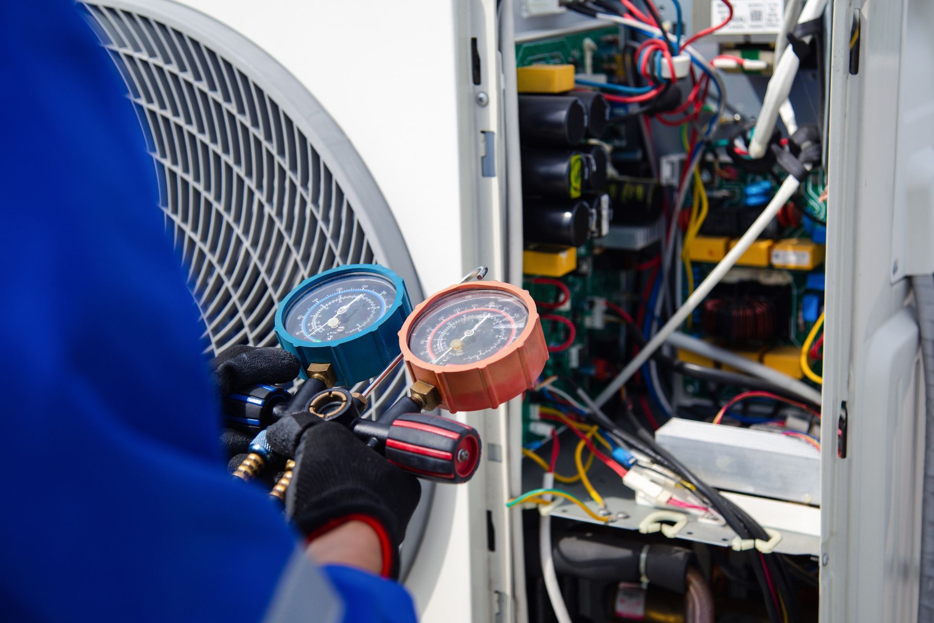 Close-up of a technician, using a gauge to measure the refrigerant pressure, for AC repair services.