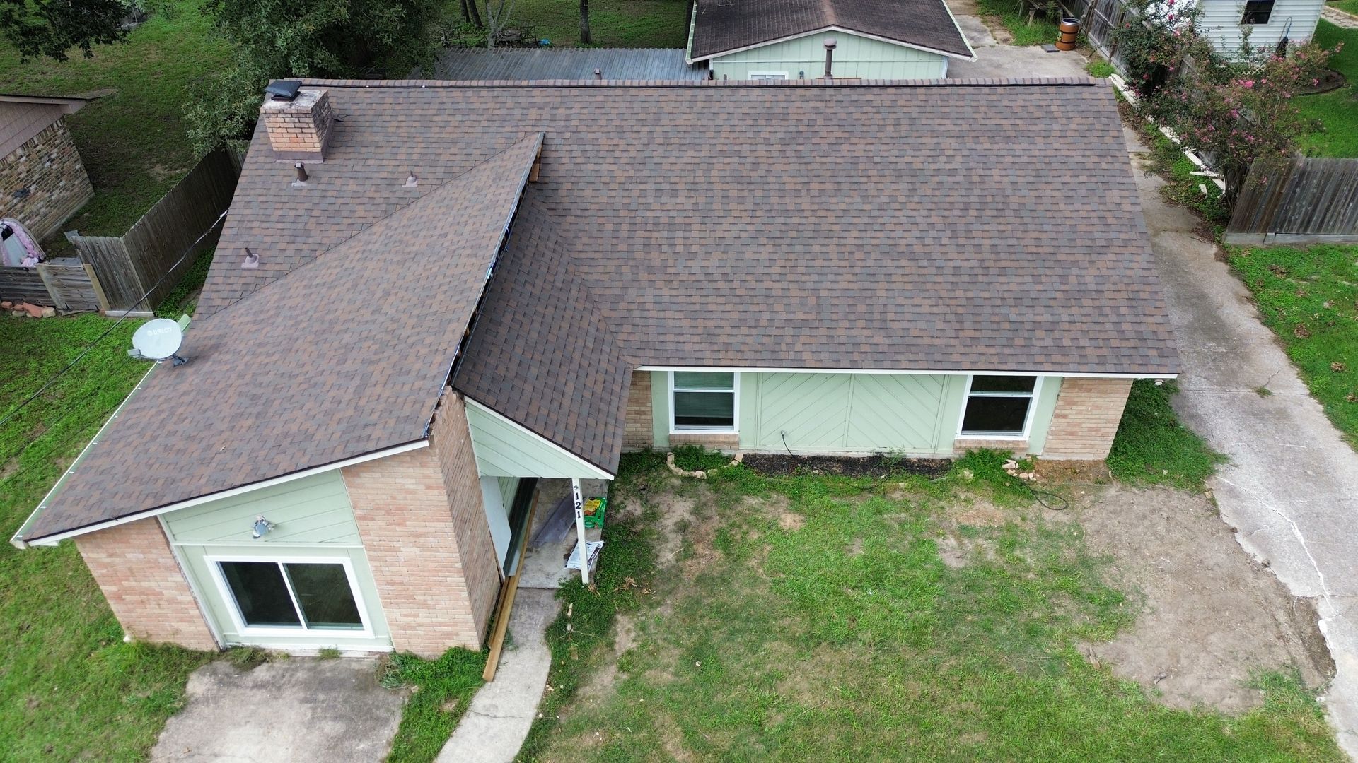 An aerial view of a brick house with a new roof.
