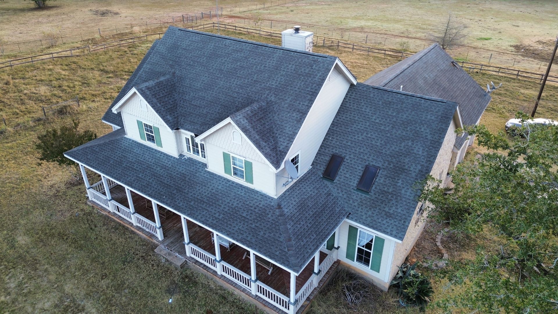 An aerial view of a large white house with a large porch.