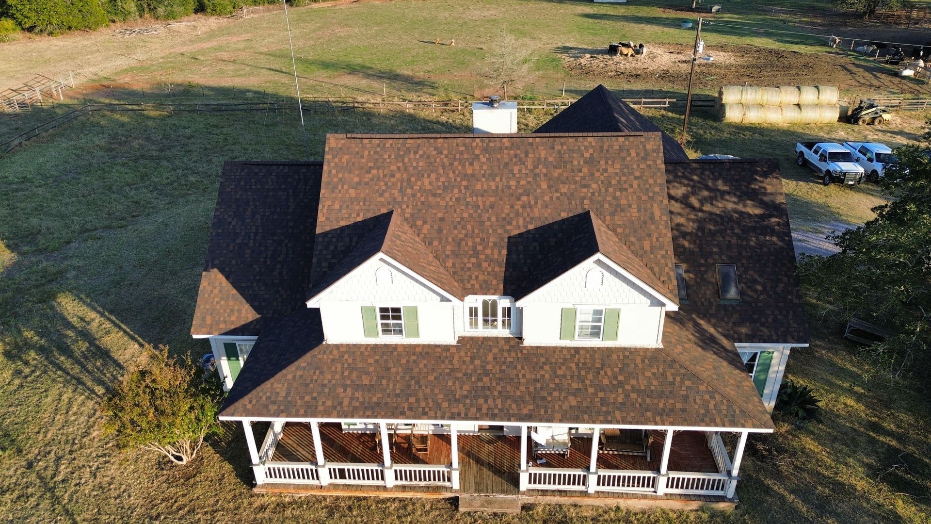 An aerial view of a large white house with a brown roof