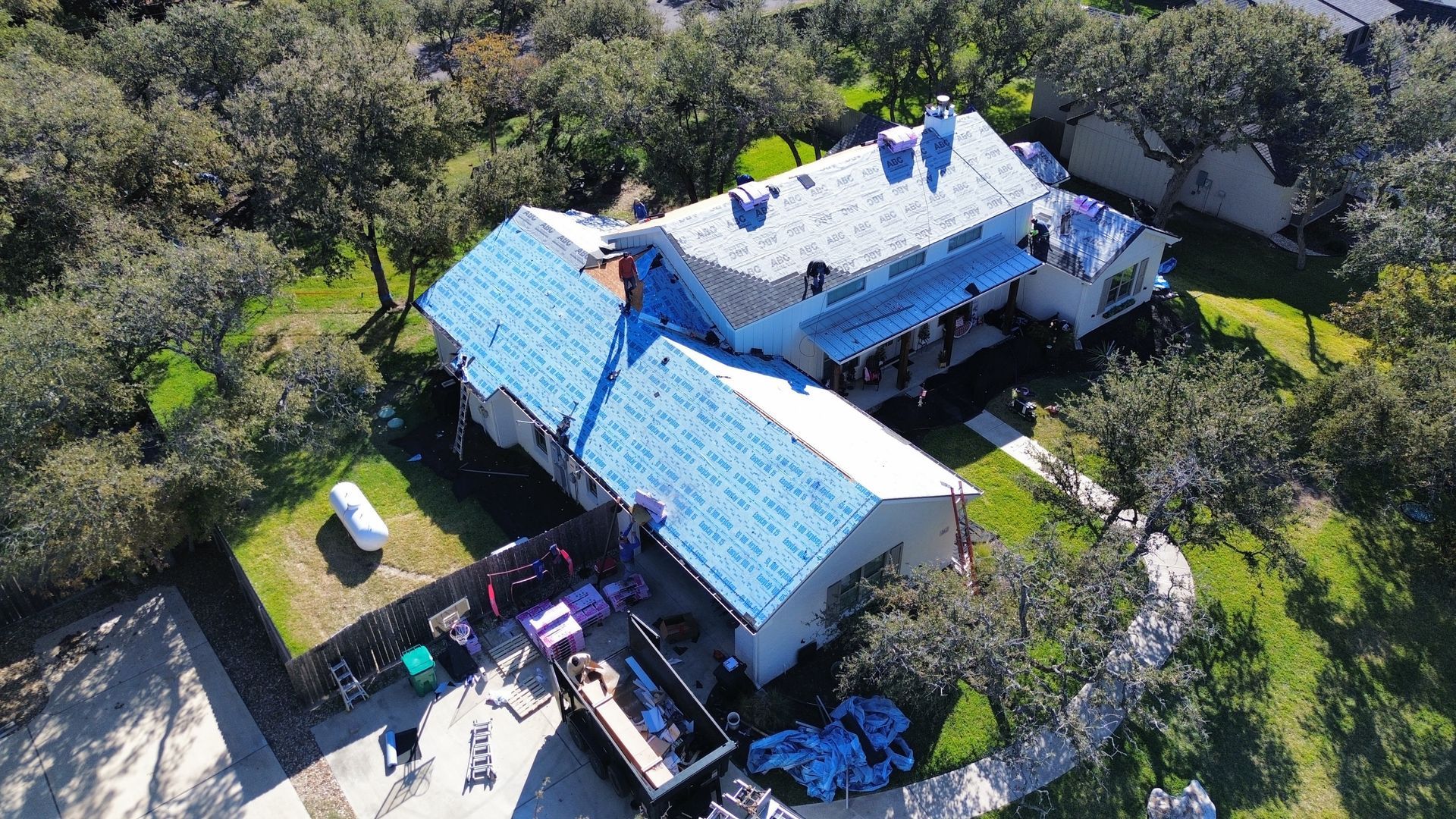 An aerial view of a house with a blue roof being installed.