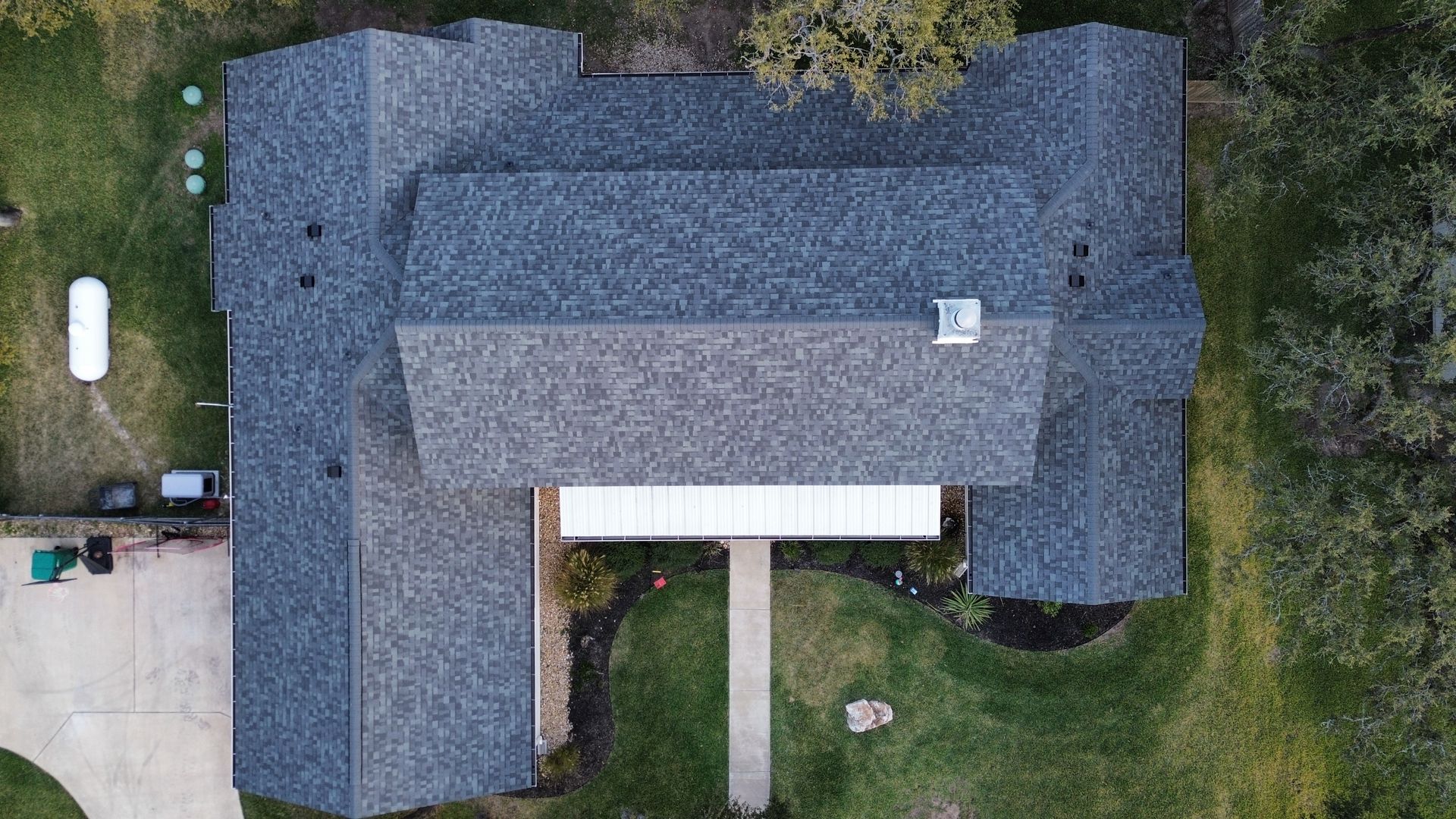 An aerial view of a house with a roof and a driveway.