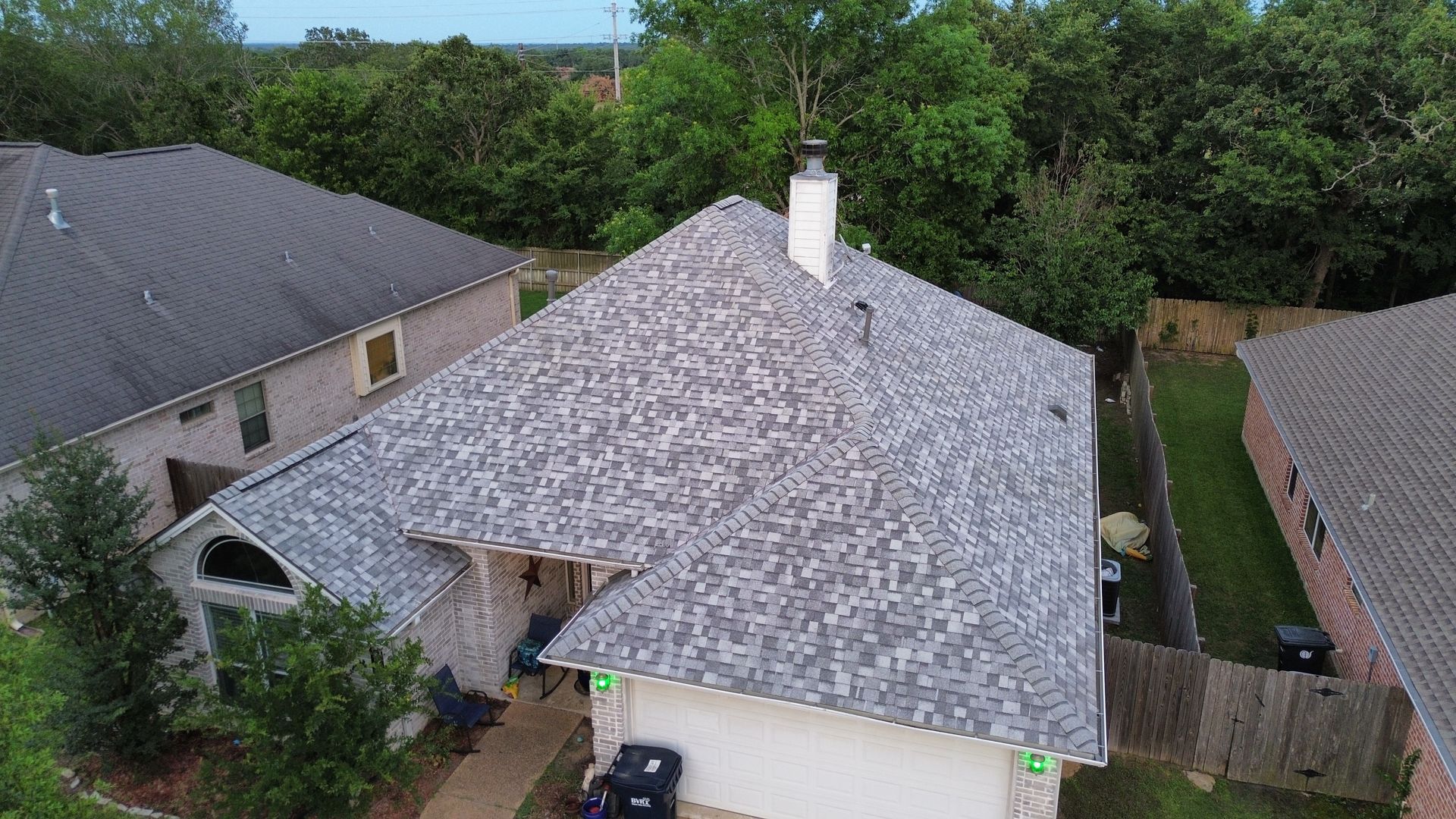 An aerial view of a large white house with a blue roof surrounded by trees.
