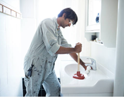 A man in overalls unblocking a sink, illustrating a hands-on approach to fixing blocked drains.