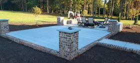 Brick patio with seating area, four brick pillars, and a grassy background.
