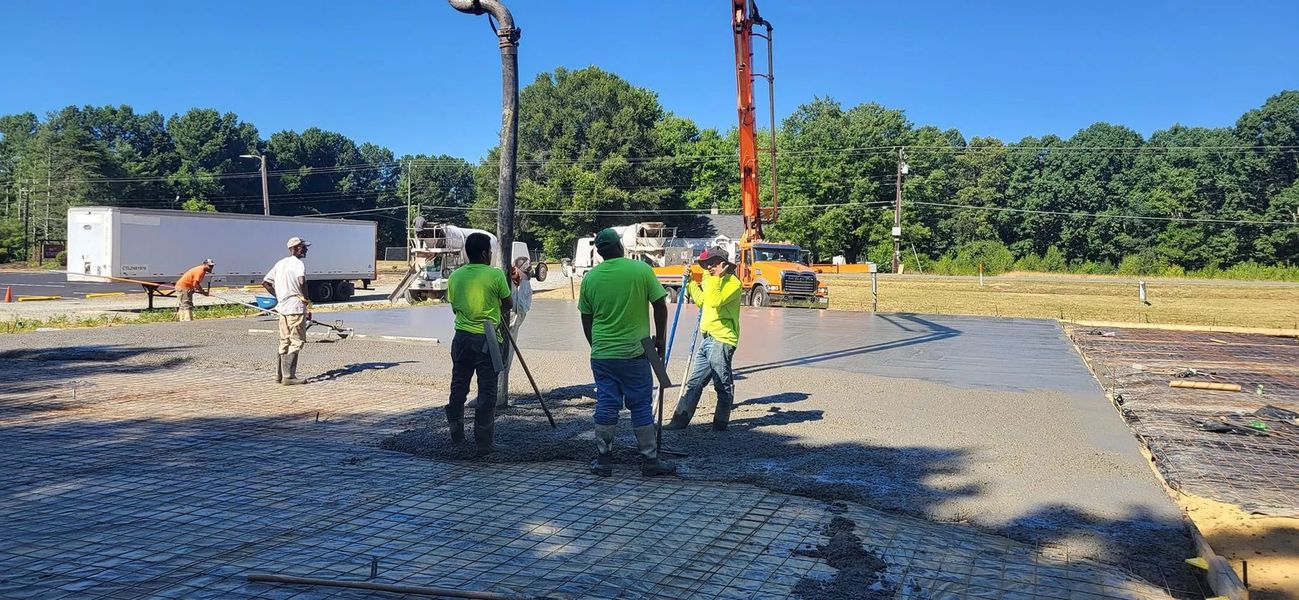 Construction workers pouring concrete on a worksite on a sunny day.