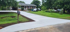 A house with a newly paved driveway, grass and a mailbox in the foreground.