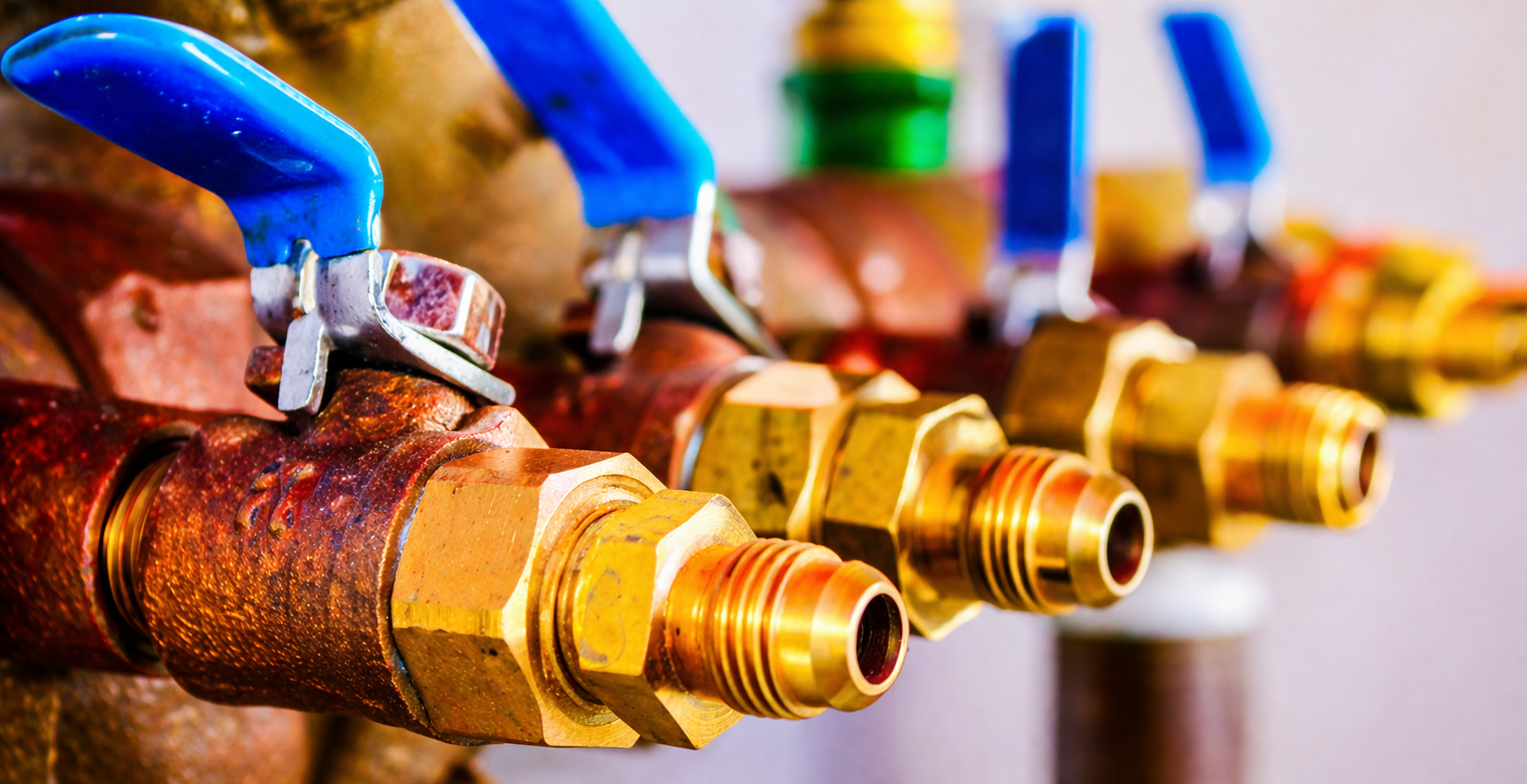 A technician in blue coveralls uses diagnostic tools to inspect metal plumbing fixtures inside a wooden cabinet.