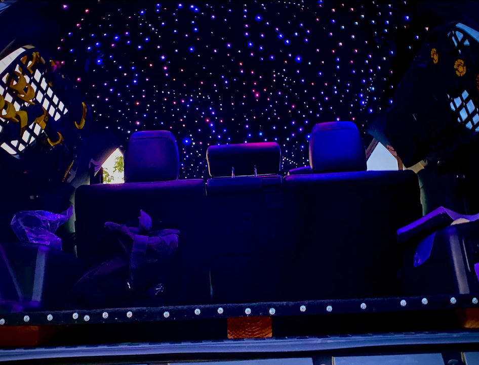A couch is sitting under a starry sky in a dark room.