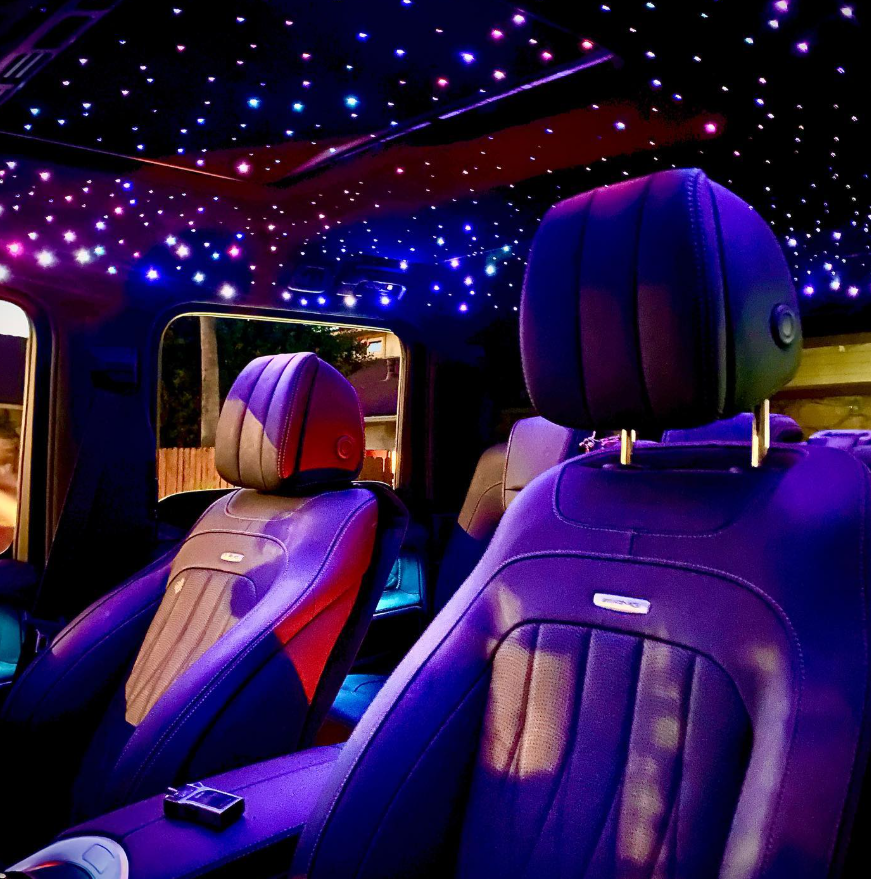 The inside of a car with purple seats and a starry ceiling