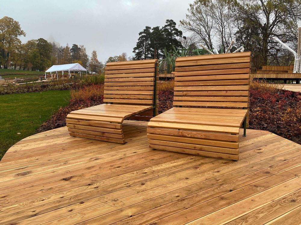 Two wooden chairs are sitting on top of a wooden deck.