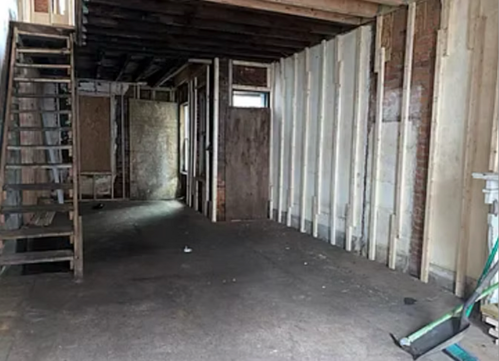 A room with a staircase and a broom in it.