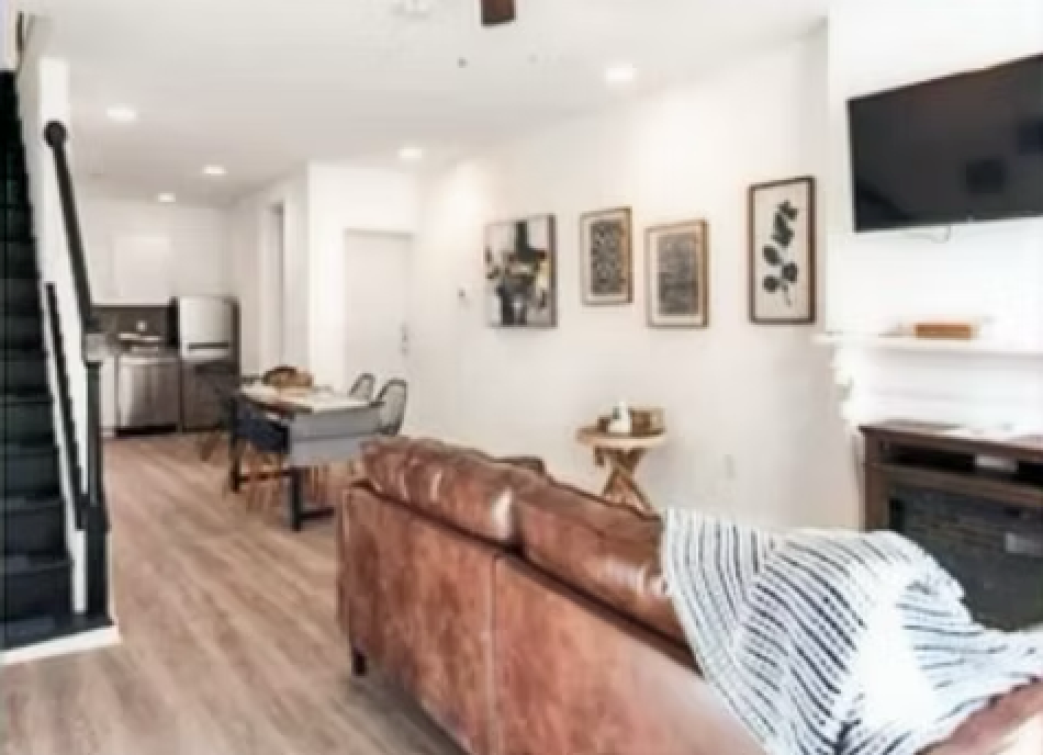 A living room with a brown leather couch and a flat screen tv.