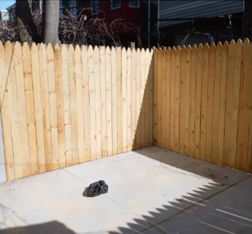 A wooden fence is surrounding a concrete patio