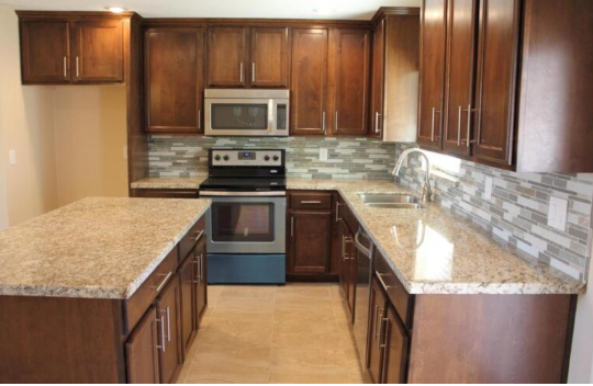 An empty kitchen with wooden cabinets and granite counter tops