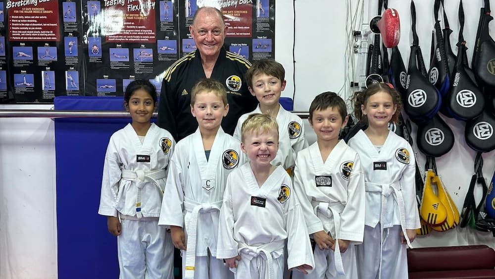 a group of young children are posing for a picture with a man in a taekwondo uniform — Tae Kwon Do Lessons in Port Stephens
