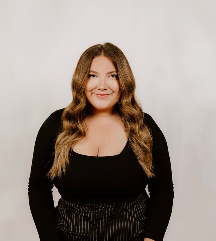 A woman wearing a t-shirt and a necklace is smiling for the camera.