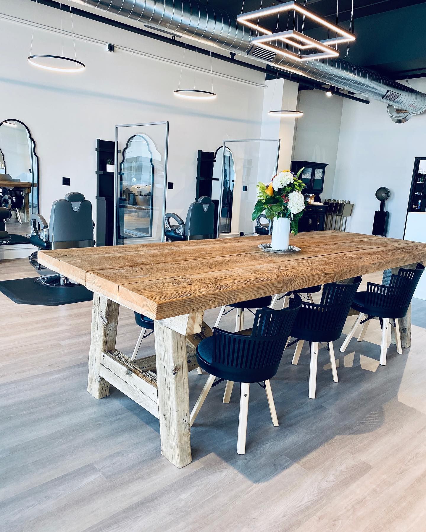 A wooden table and chairs in a room with a vase of flowers on it.