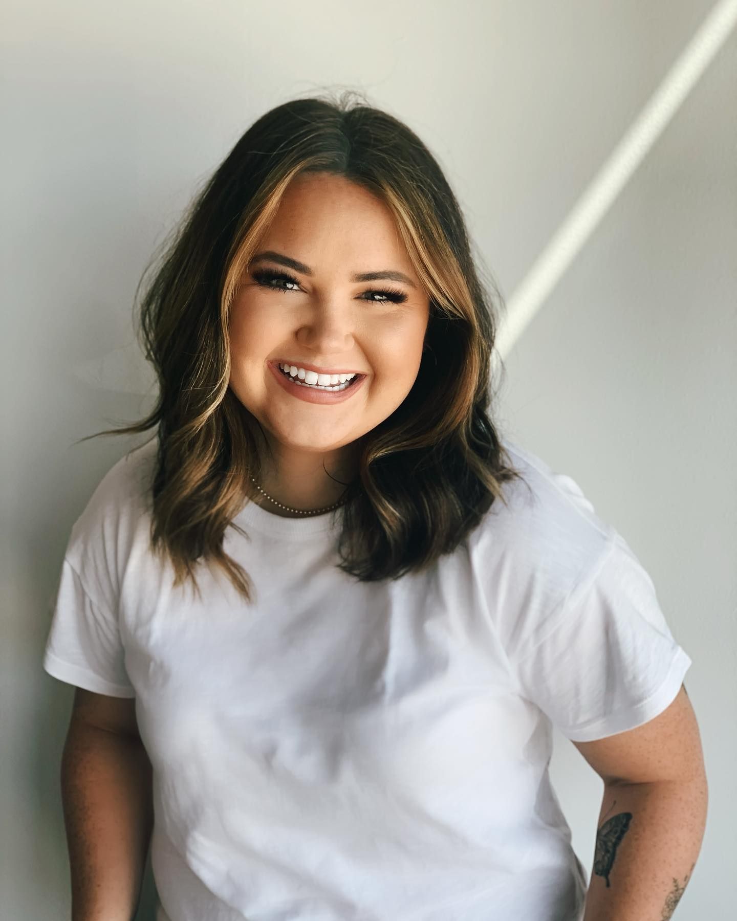 A woman wearing a white t-shirt is smiling for the camera.