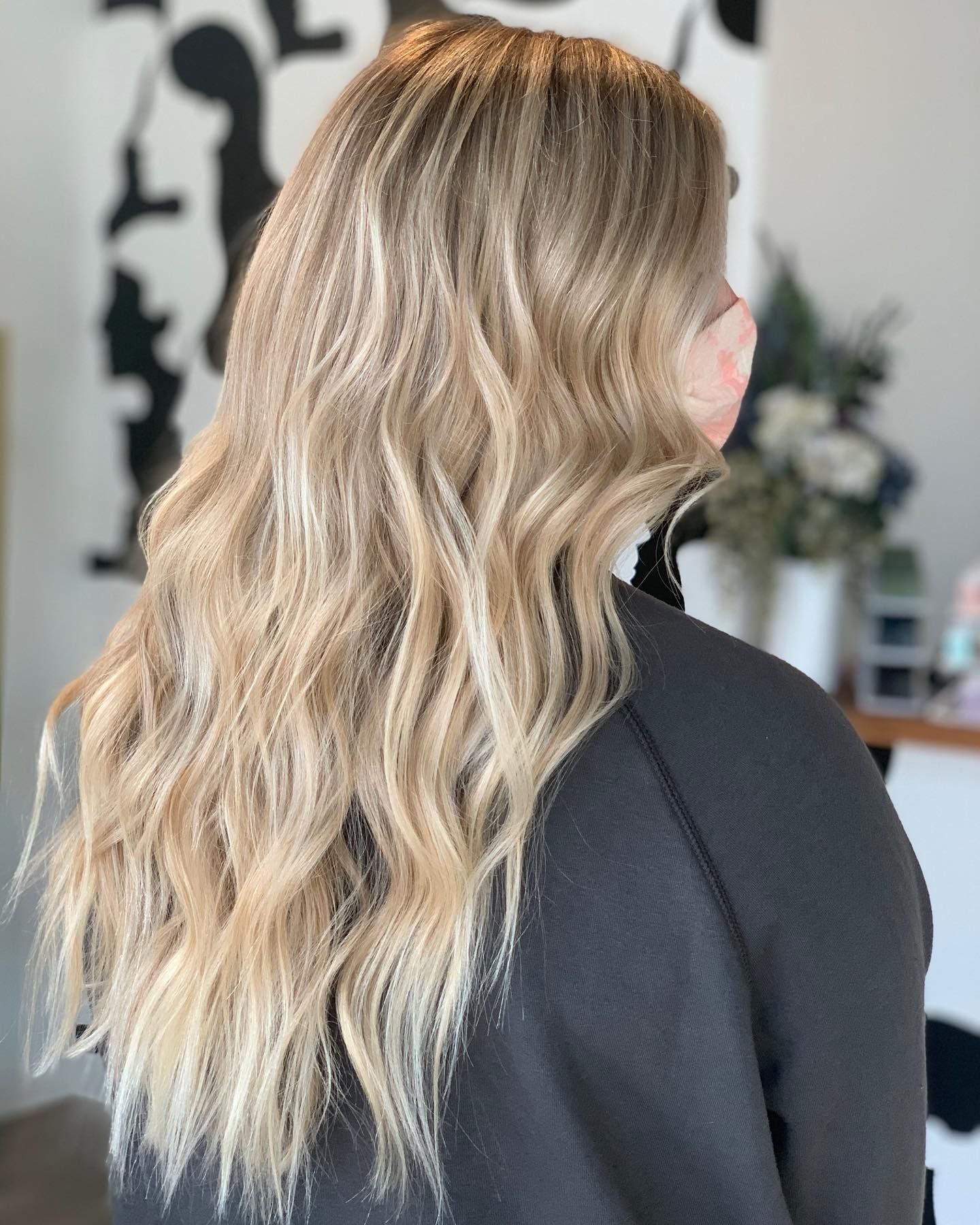 A woman with long blonde hair is wearing a black sweater.